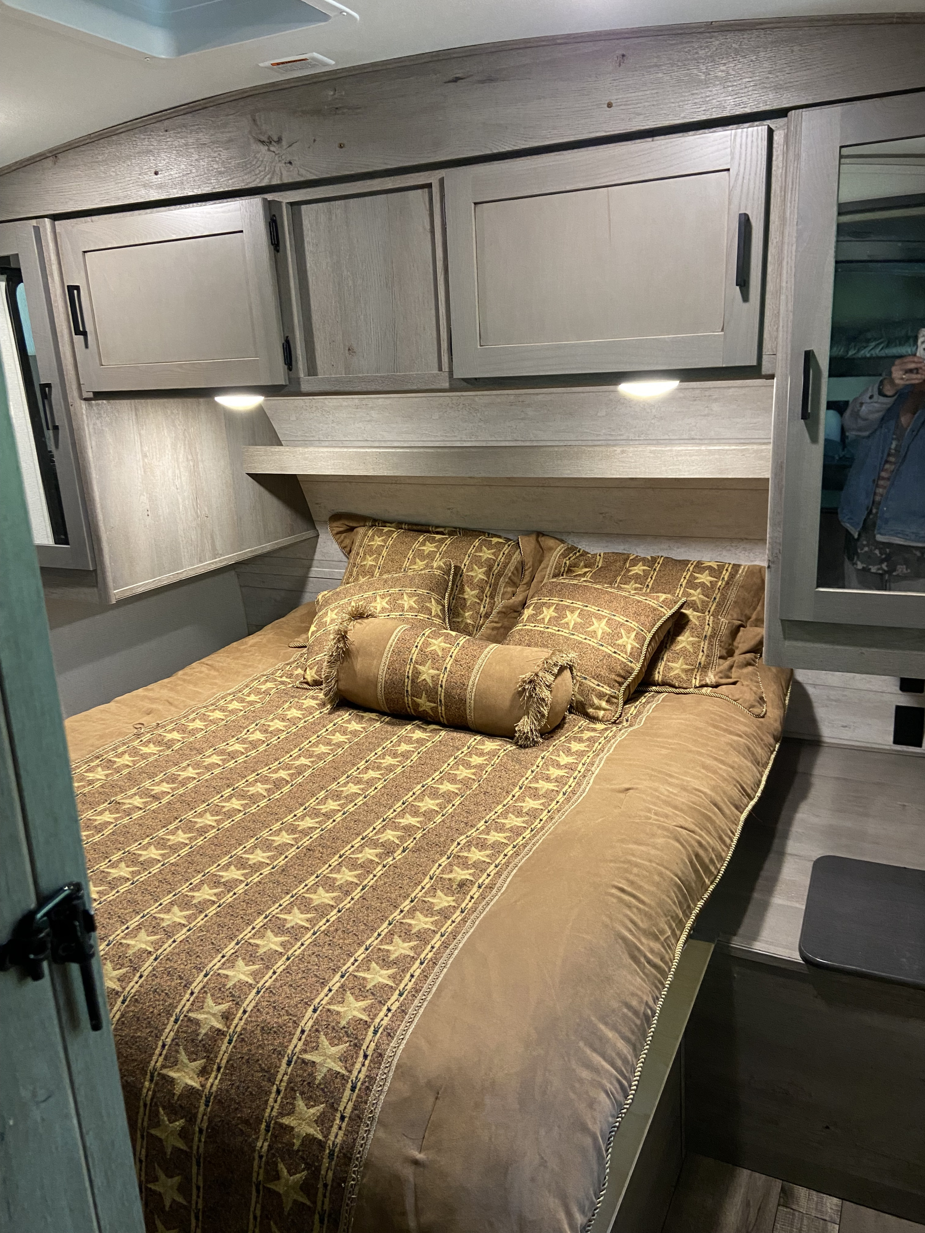 Cozy RV rental bedroom with star-patterned bedding, overhead cabinets, and soft lighting.. Keystone RV Outback 2021