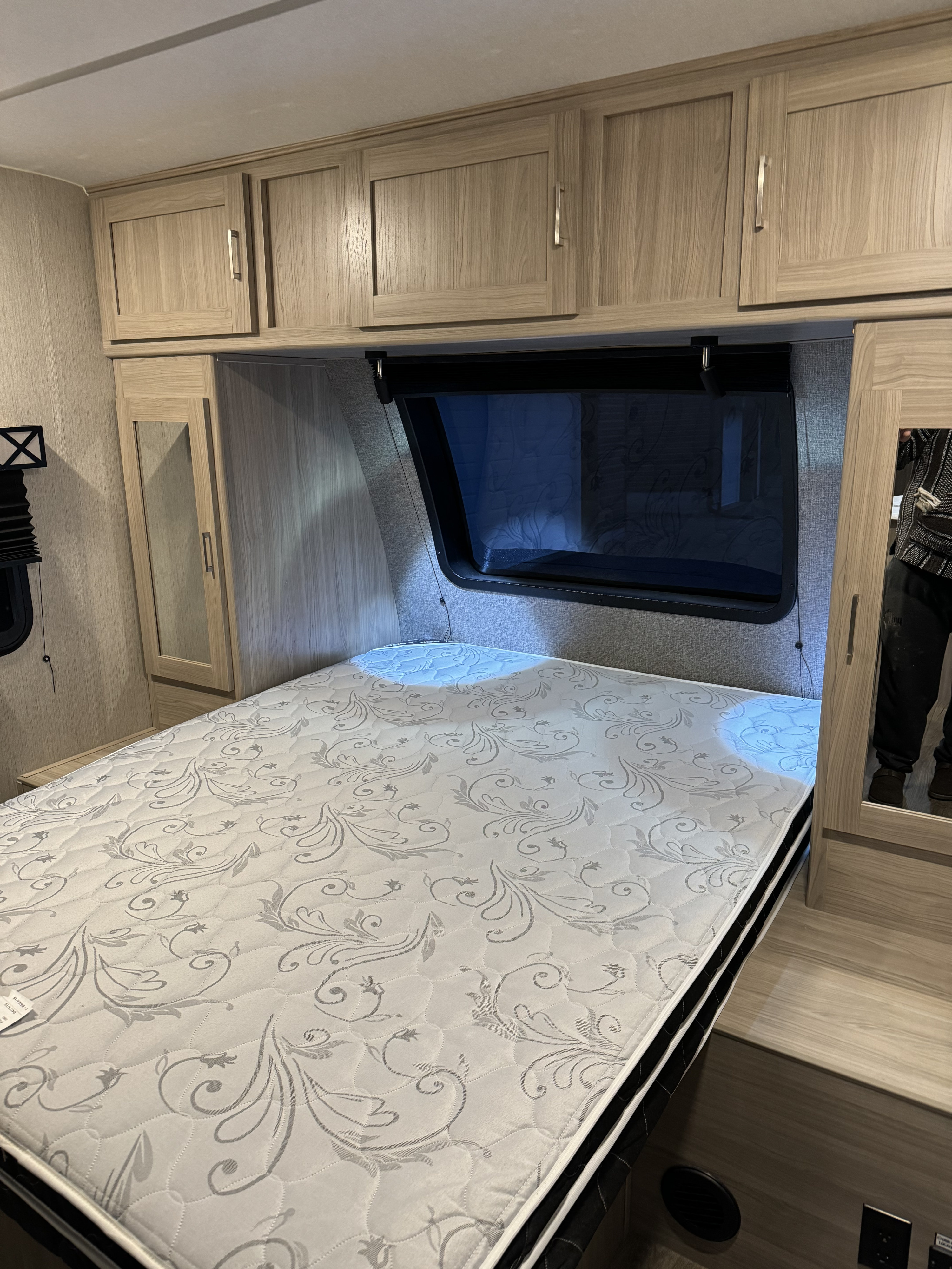 Comfortable RV rental bedroom: patterned mattress, wooden overhead cabinets, and mirrored wardrobe for your journey.. Coachmen Freedom Express 2020