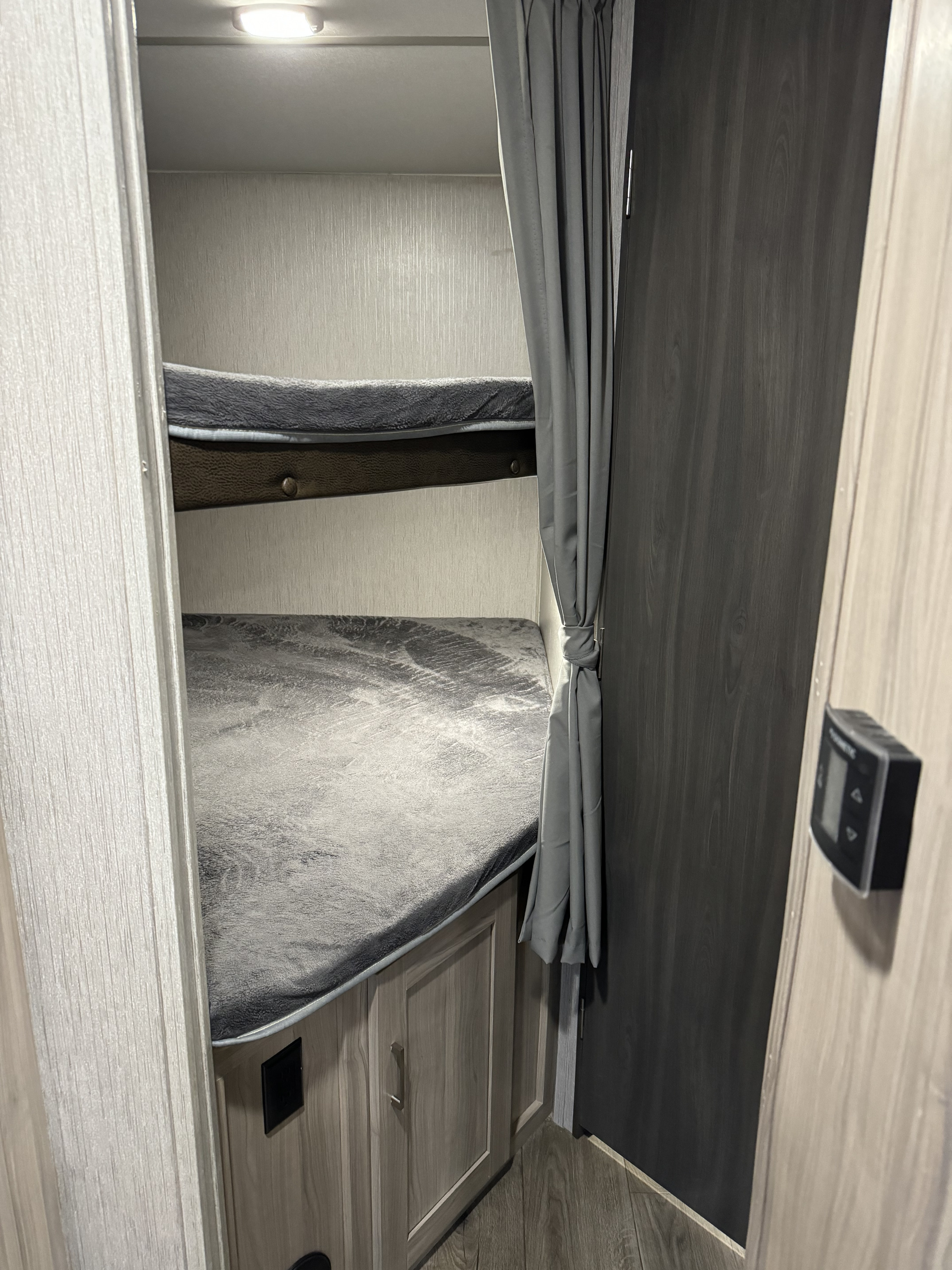 RV rental interior: Two cozy bunk beds with soft grey bedding, light textured walls, and a Dometic climate control panel.. Coachmen Freedom Express 2020