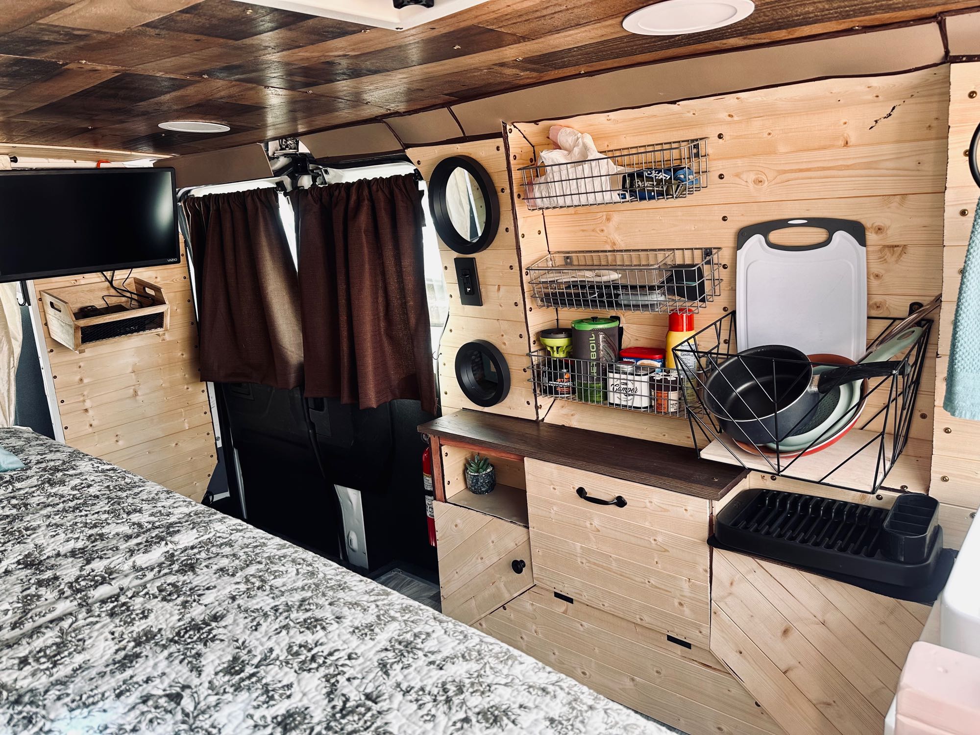 Inside an rv rental: a custom camper van with warm wood paneling, a compact kitchen, smart storage, and cozy bed.. FORD TRANSIT 250 2015