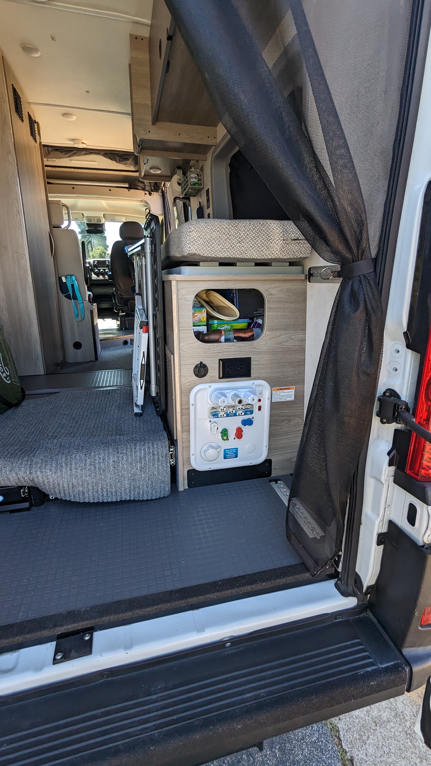 RV rental interior: open rear door reveals a versatile living space with adaptable seating, storage, and utility panel.. Winnebago Solis 59PX 2023