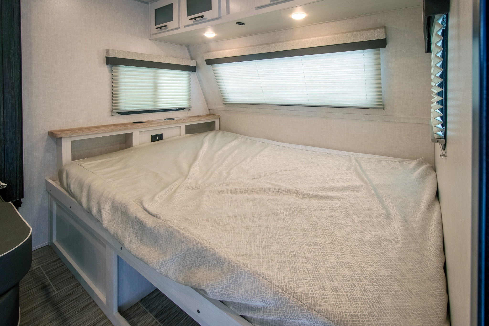 Cozy RV rental bedroom featuring a comfortable bed, windows with blinds, and integrated storage units.. No Boundaries 19.8 2024