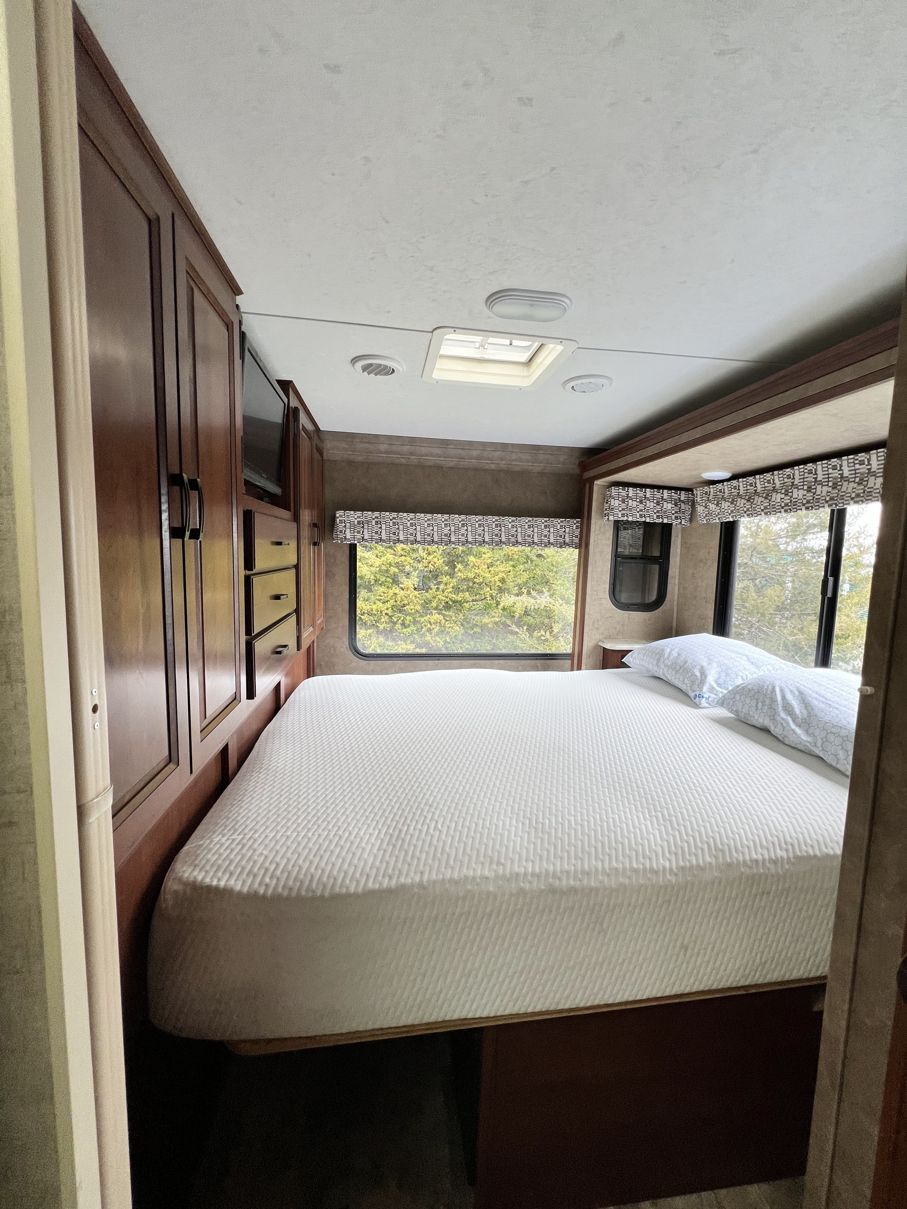 Another shot of the master - when popped out there is about 12 inches of walk-way at the foot of the bed, and the small side windows let people look out the window while sleeping or open them for a little fresh air flow.
This master has a curtain for privacy, but as mentioned, the bathroom door can be opened and locks into place via a magnet to create privacy between the master and main cabin. It's super clever. Have we mentioned it is super clever?. Forest River Sunseeker 2016