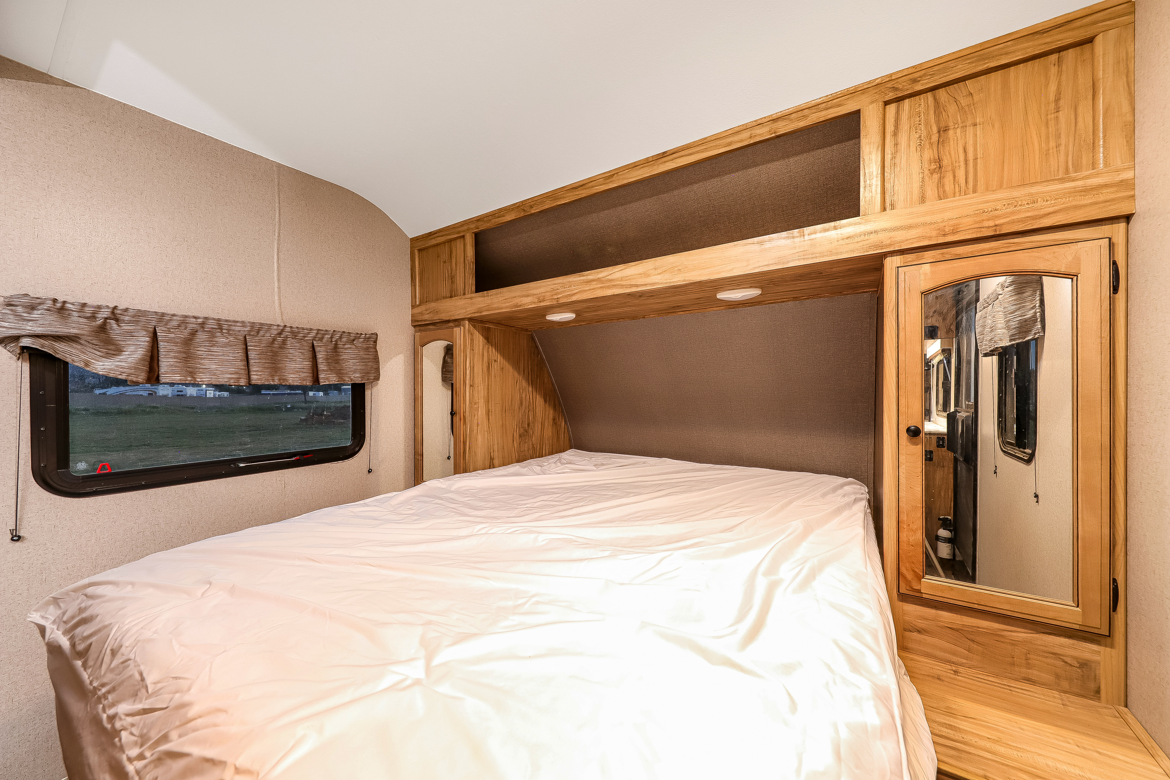 Cozy RV rental bedroom with a comfortable bed, window, and integrated wooden cabinetry offering smart storage and lighting.. Coachmen Freedom Express Select 31SE 2018