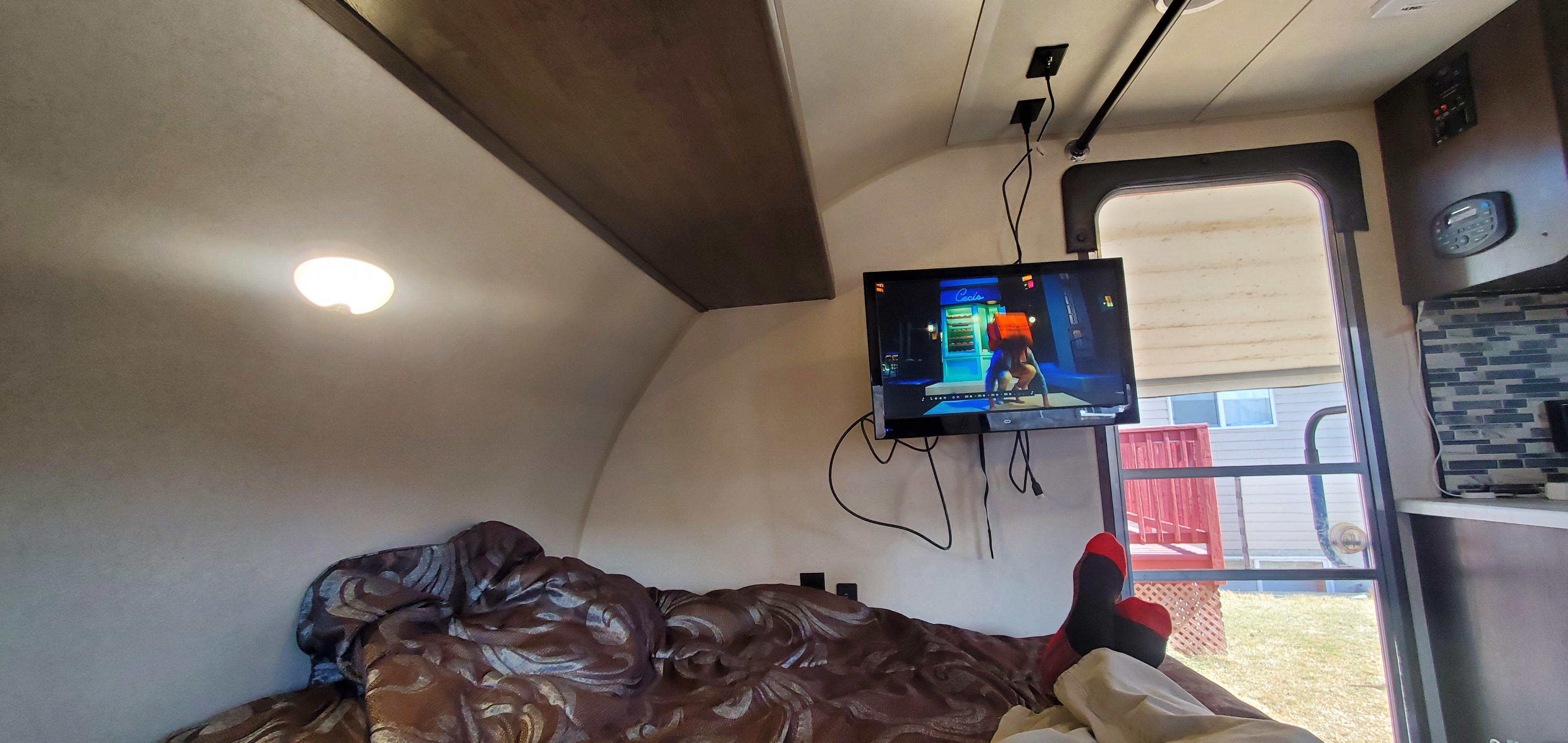 Cozy RV rental interior with a bed and TV. Someone's relaxing with their feet up, enjoying entertainment.. Forest River Salem FSX 2019