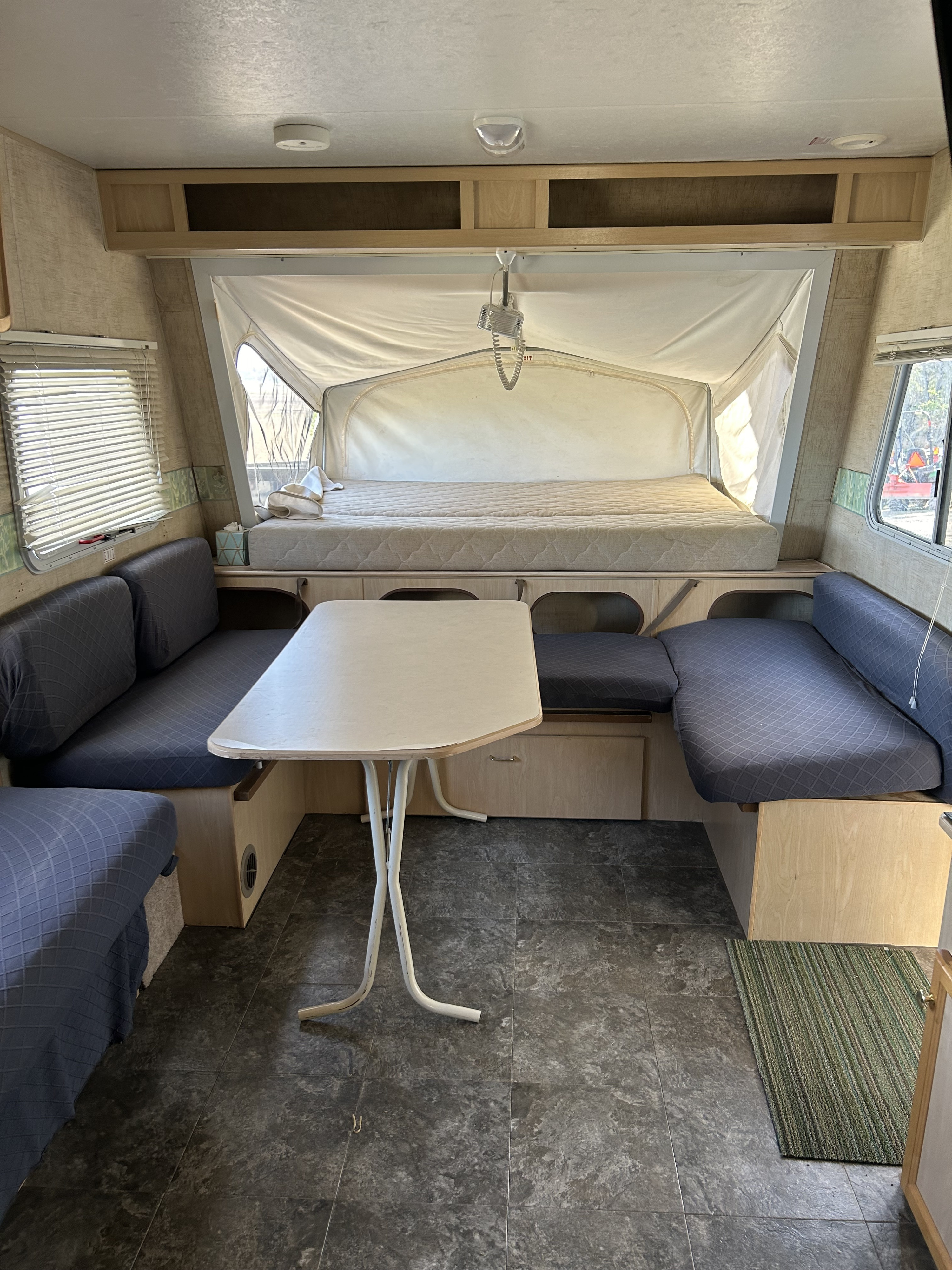 Inside this RV rental: a pop-up camper's interior with dining table, bench seating, and rear bed for guests.. Jayco Jay Feather EXP 2004