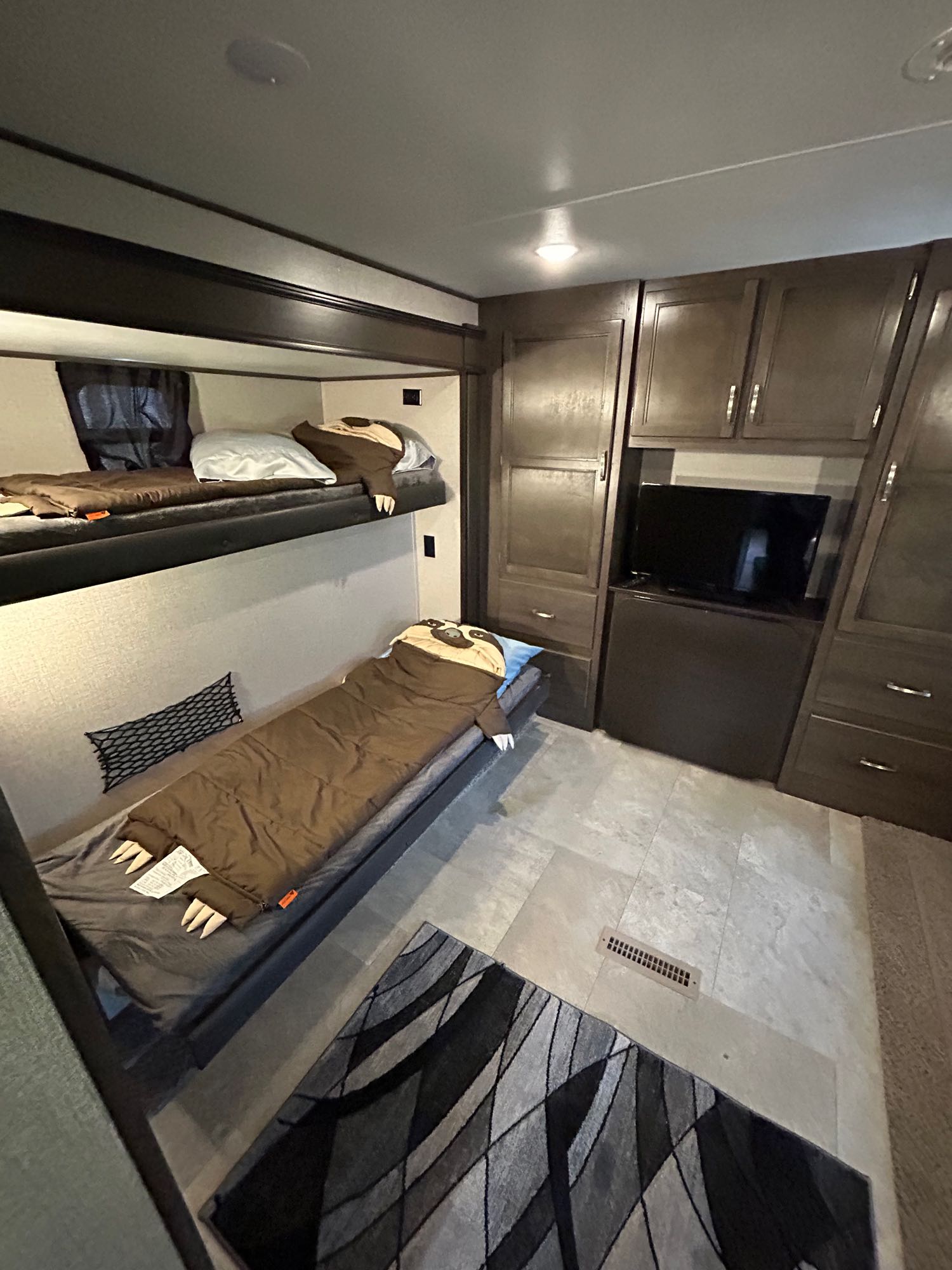 Inside an **rv rental**: A cozy bunk room with stacked beds featuring fun sloth sleeping bags, a TV, and dark wood cabinetry.. Jayco Jay Flight 2020