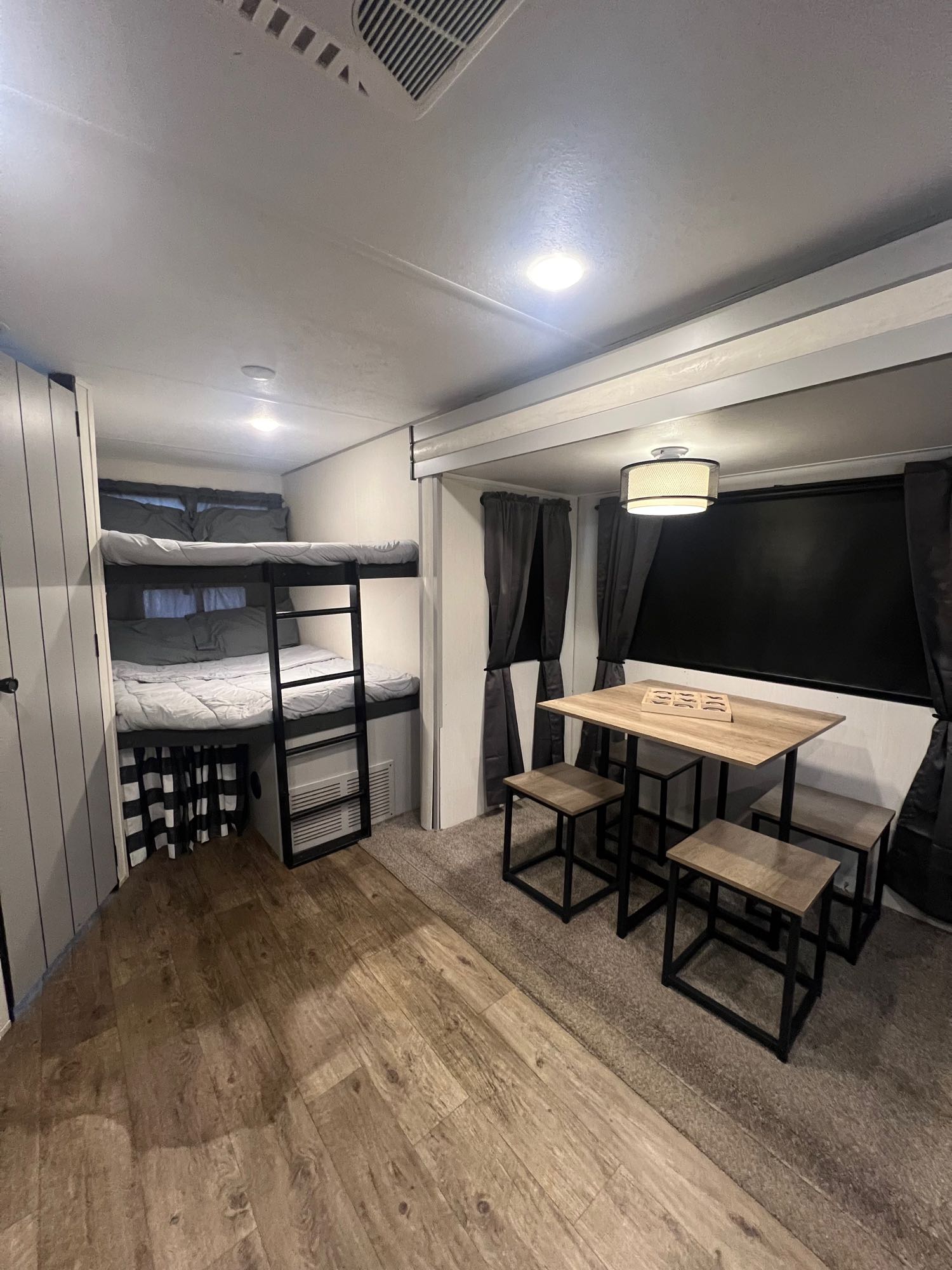 RV rental interior: bunk beds with ladder, dining table with four stools. Cozy, functional space.. Forest River Vibe 2021