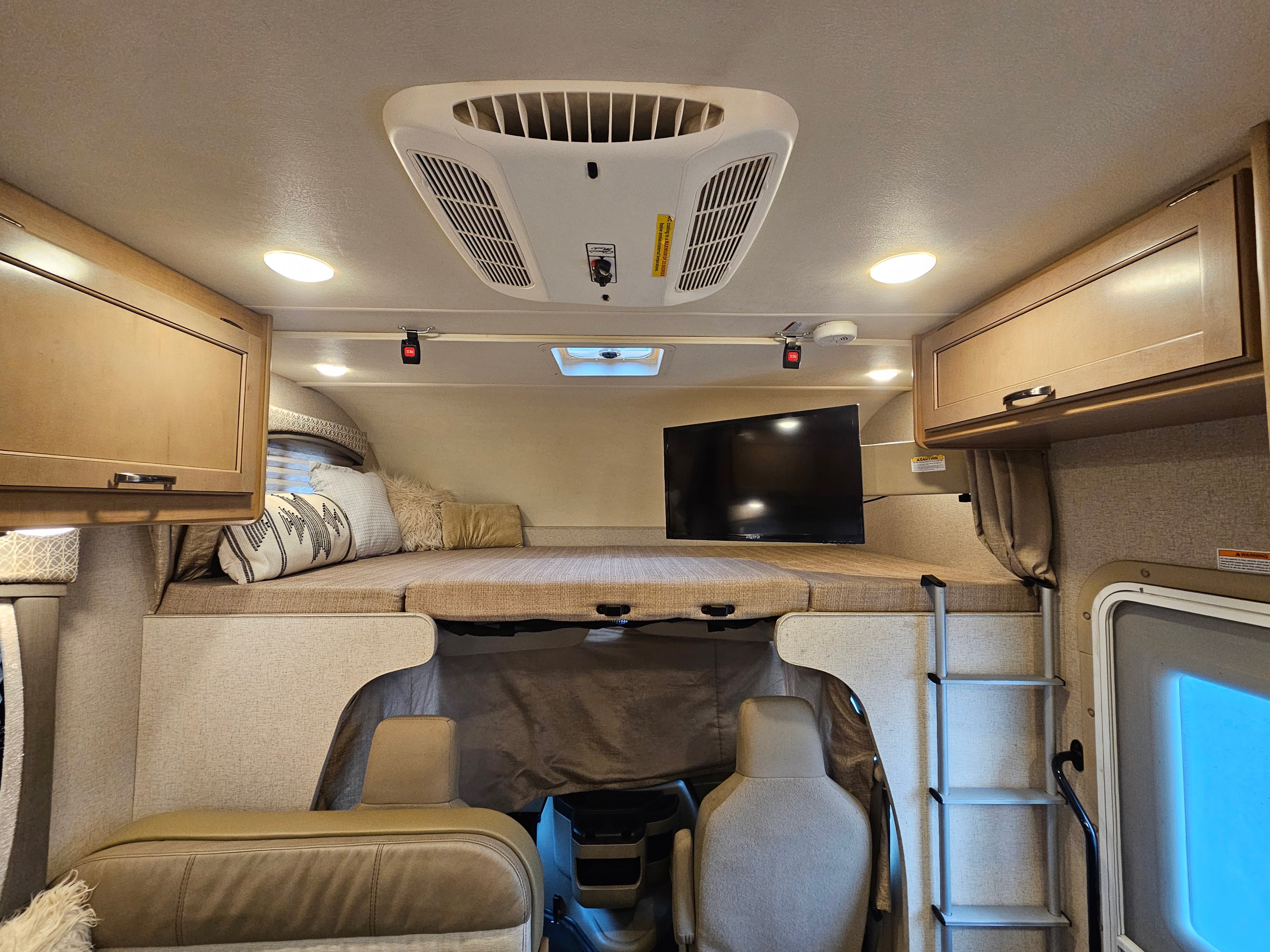 RV rental: Cozy bunk bed with TV & AC in a modern camper interior.. Thor Motor Coach Four Winds 2021