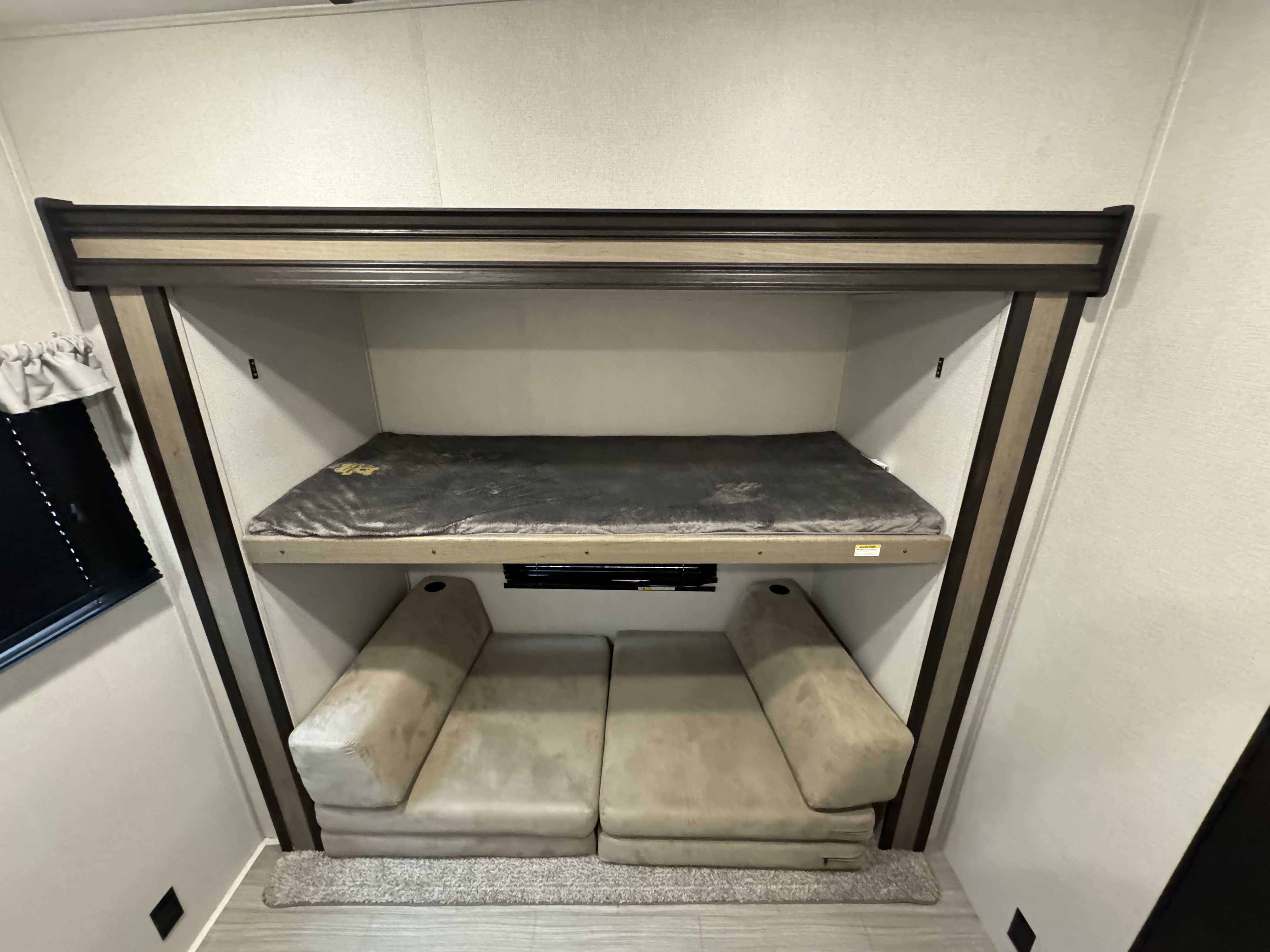 RV rental interior: a bunk bed with a plush gray mattress pad above a convertible lower sofa, perfect for compact sleeping.. Keystone RV Hideout 2021