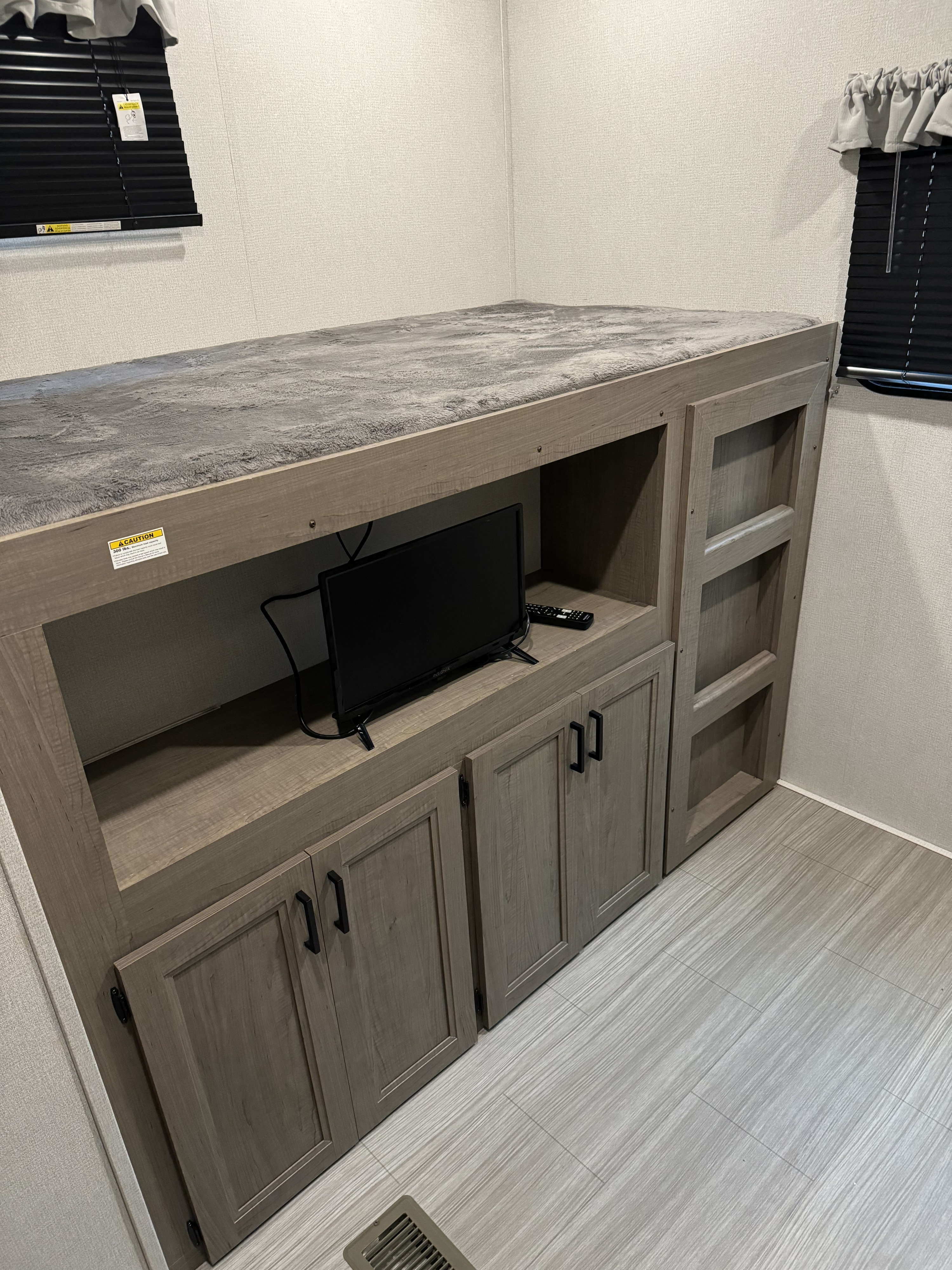 RV rental: Space-saving bunk bed with gray blanket, TV, and light wood storage cabinets, maximizing comfort.. Keystone RV Hideout 2021