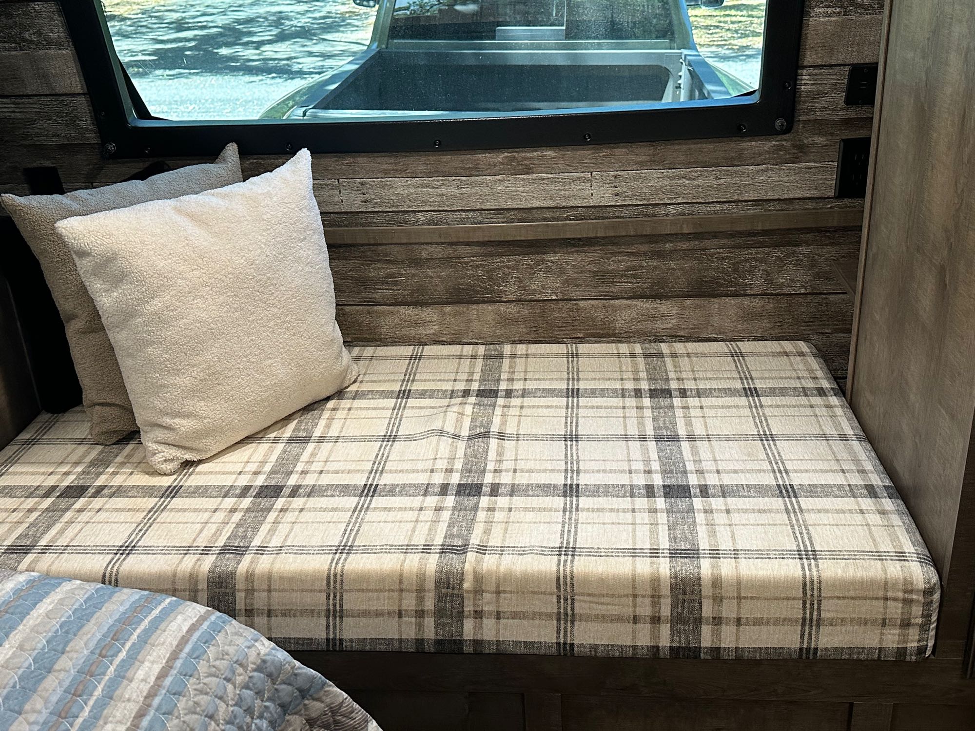 Cozy RV rental interior: wood-accented walls, plaid bench, plush pillows, & window view for travel comfort.. Venture STT343VIB 2022