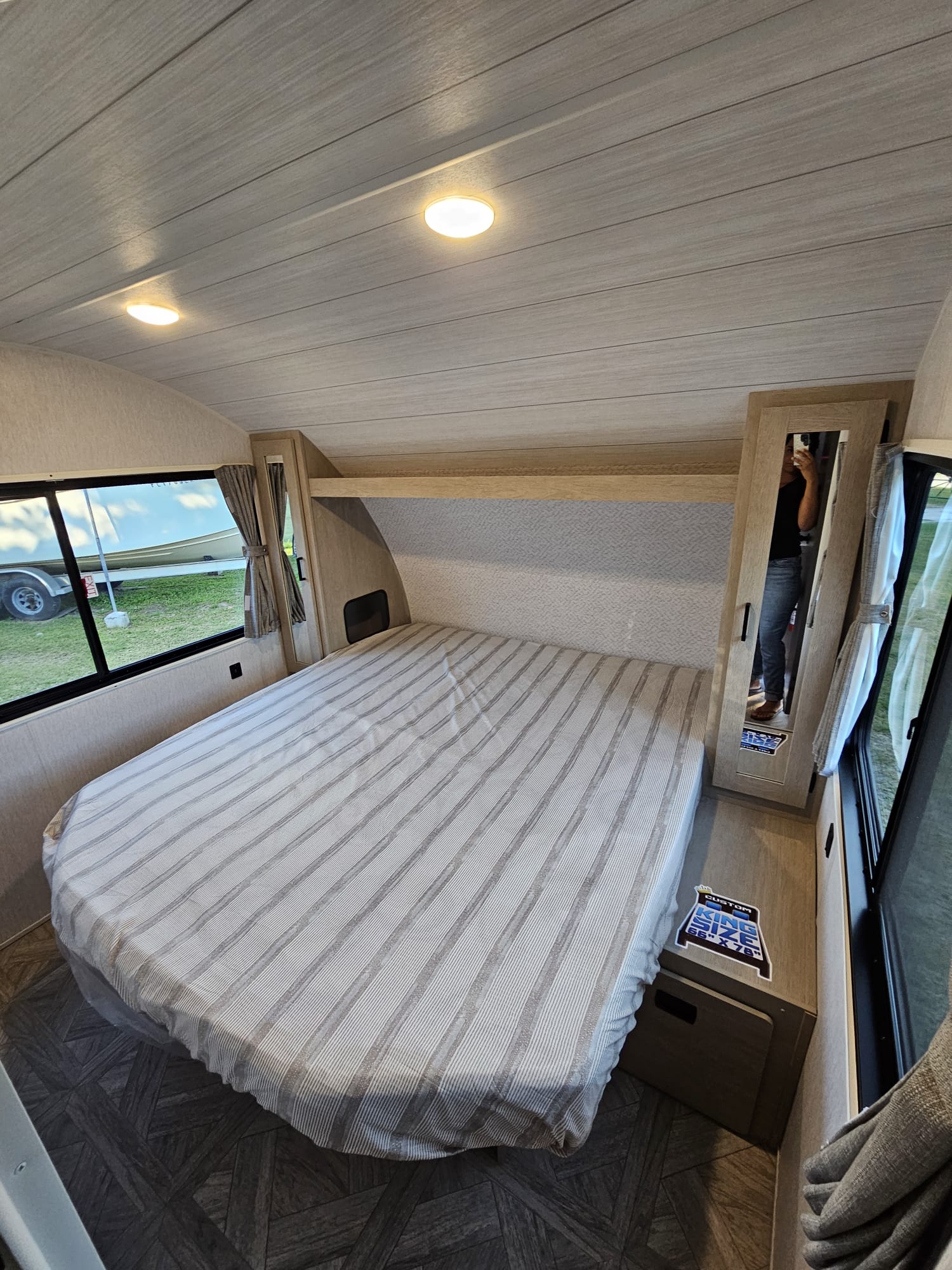 Spacious RV rental bedroom featuring a custom king-size bed, mirrored closet, and large windows. Perfect for mobile living.. Forest River Wildwood X-Lite Platinum 2024