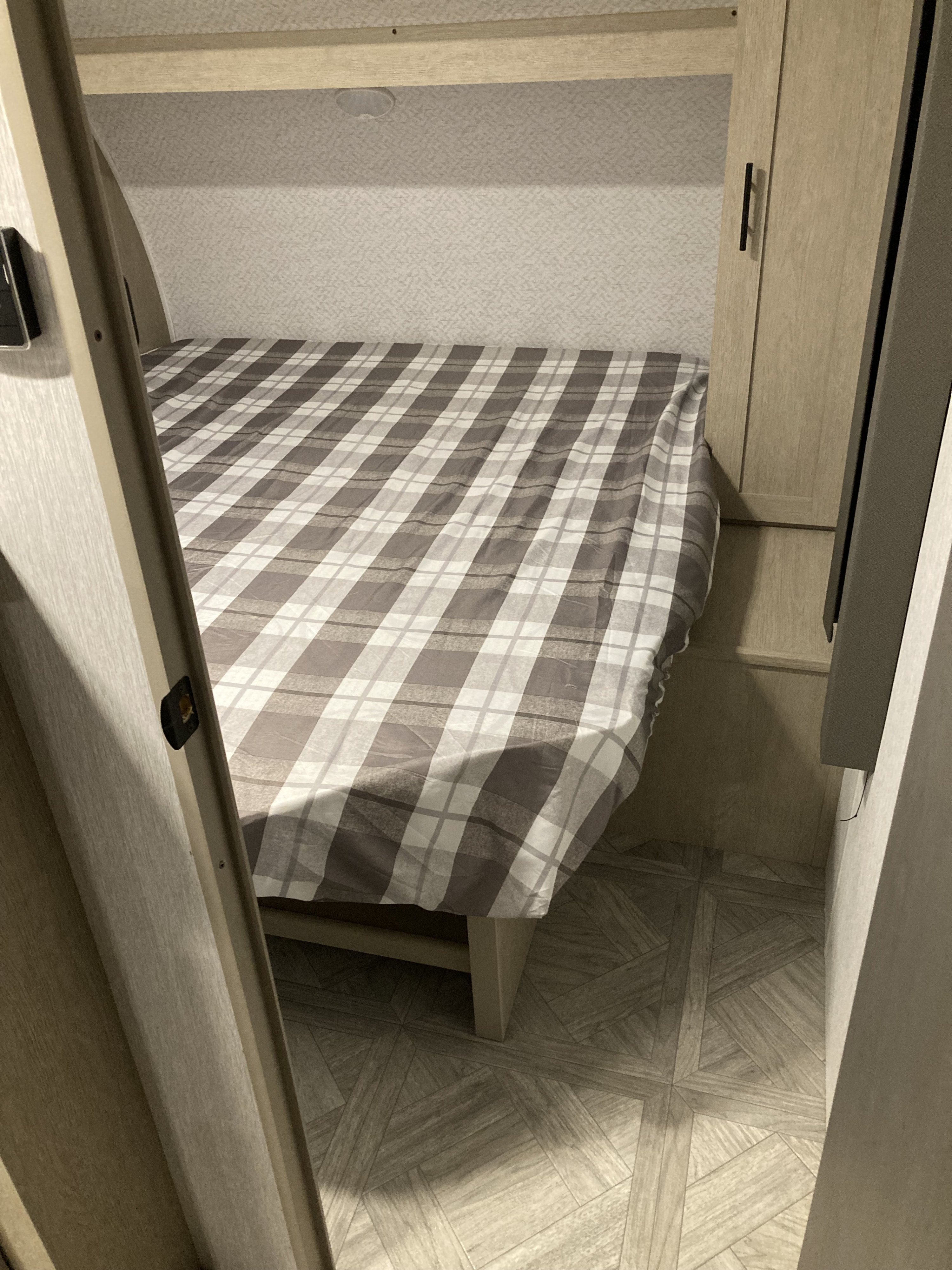 Cozy RV rental bedroom with plaid bedding and integrated storage.. Forest River Salem Cruise Lite 2023