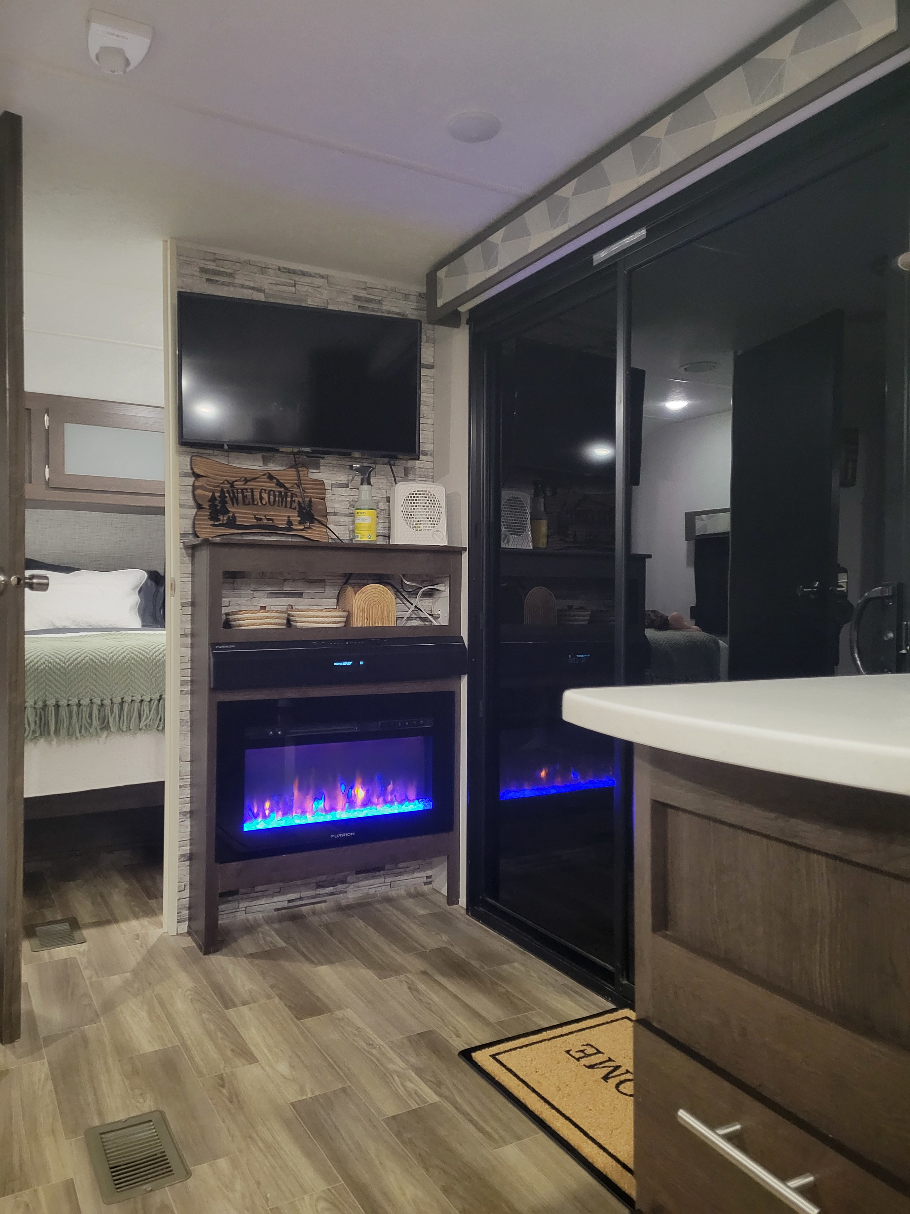 Modern RV rental interior: inviting living space with an electric fireplace, TV, and adjacent cozy bedroom. Ready for adventures!. Forest River Wildwood 2020