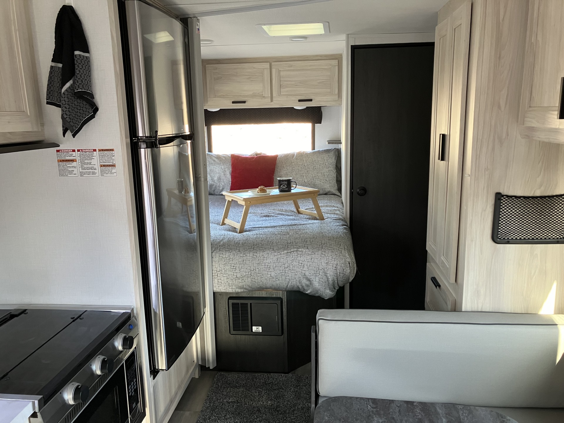 Bright RV rental interior: cozy bed with breakfast tray, compact kitchen, and seating for comfortable travel adventures.. Forester LE 2024