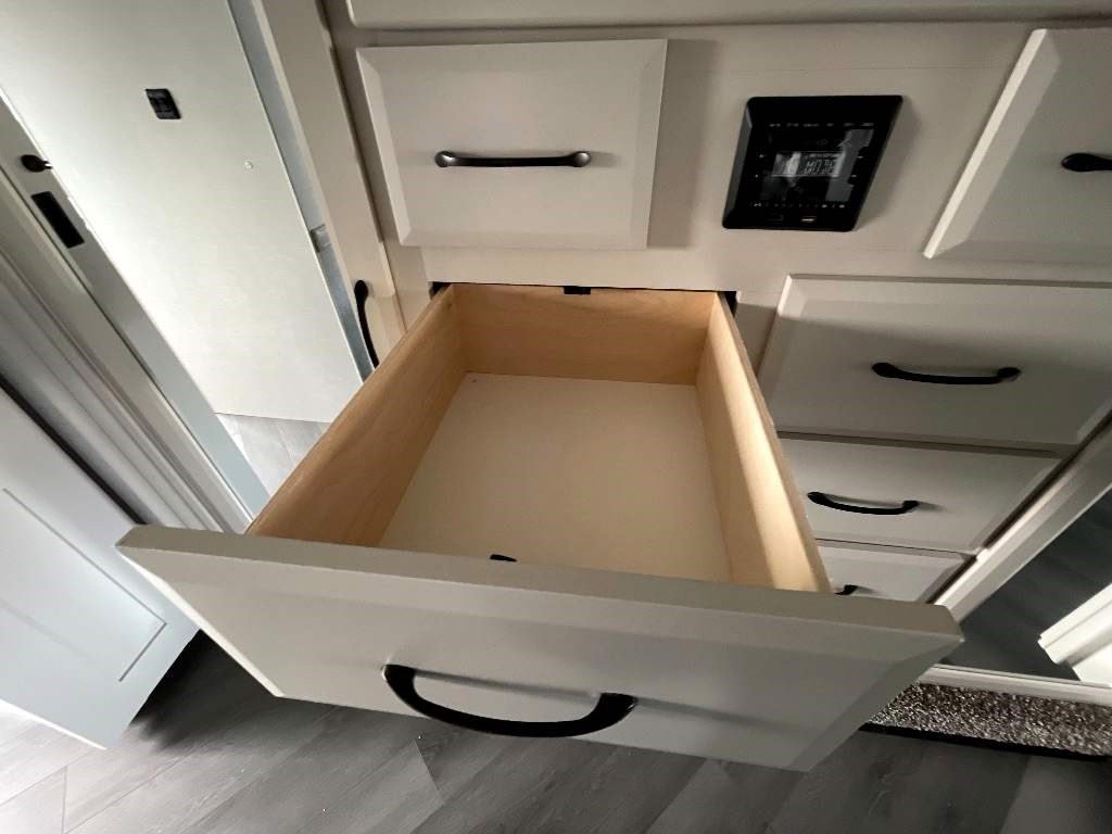 Get organized in your RV rental with this spacious cabinet unit featuring an open drawer, control panel, and more storage.. Fleetwood Fortis 2024