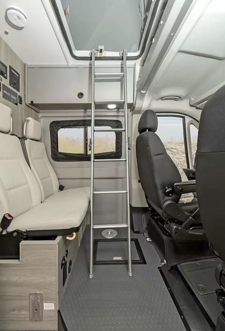 RV rental interior: Camper van living space featuring ladder to overhead bunk, passenger seating, and front cabin.. Winnebago Solis 2022
