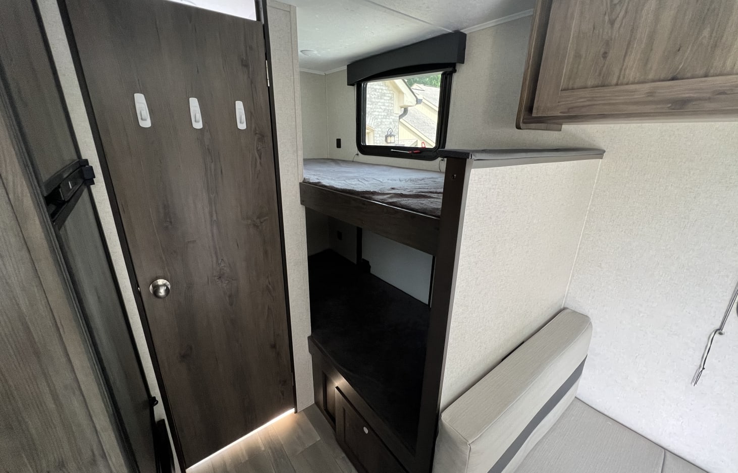 RV rental: Cozy interior showing dark door with hooks, bunk beds, a window, and a light-colored dinette bench with storage.. Clipper Ultra Lite 2022