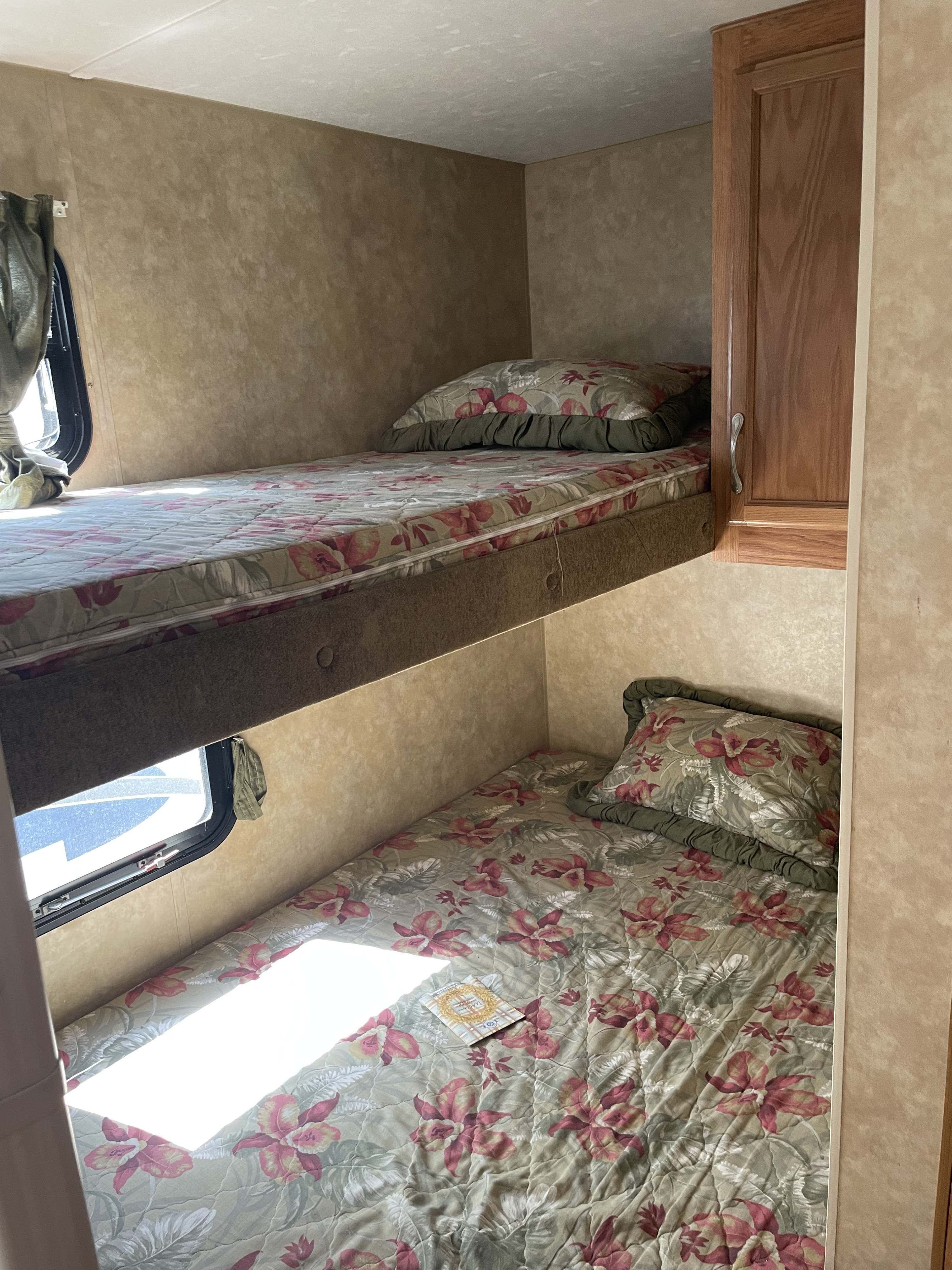 Comfortable bunk beds in an RV rental, featuring floral bedding, ideal for a cozy sleeping area with natural light.. Jayco Jay Flight G2 2008