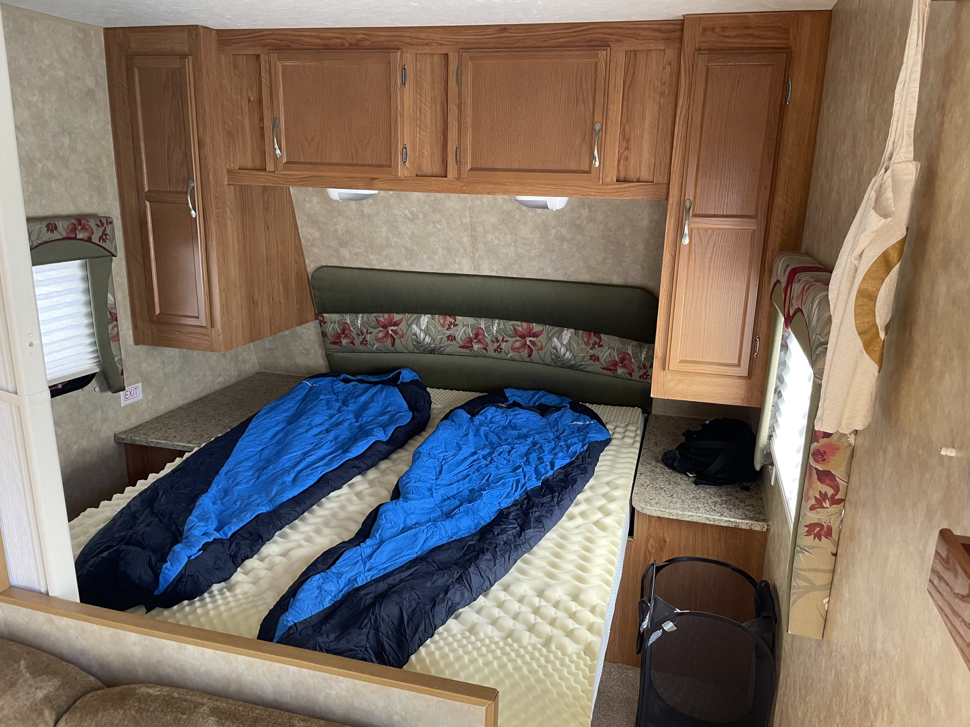 Inside an RV rental's bedroom: two sleeping bags on a foam mattress, wooden cabinets, and a floral headboard.. Jayco Jay Flight G2 2008