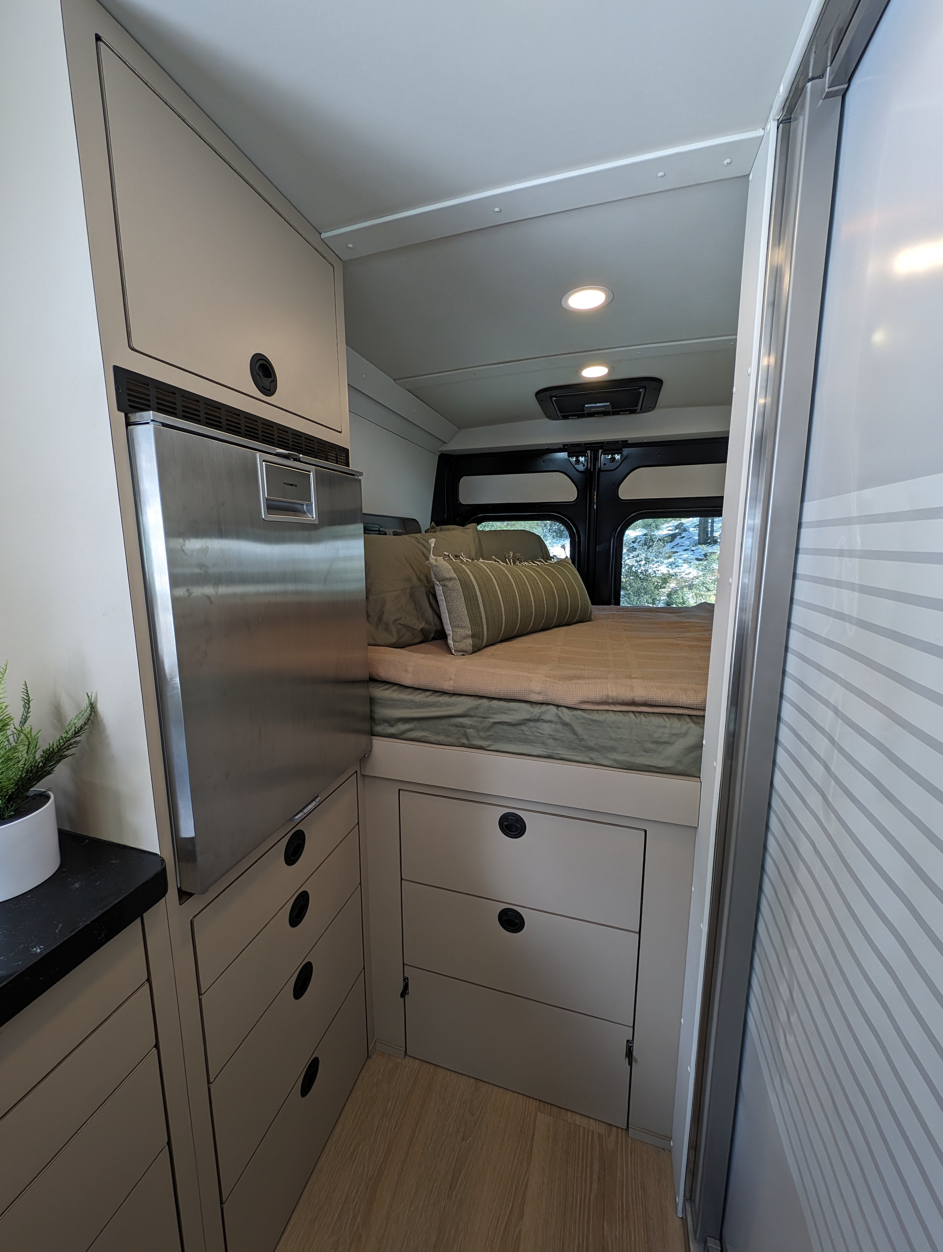 Cozy rv rental interior featuring a comfortable bed, integrated refrigerator, ample storage, and smart design.. New Life Conversions Luxury Edition 2022