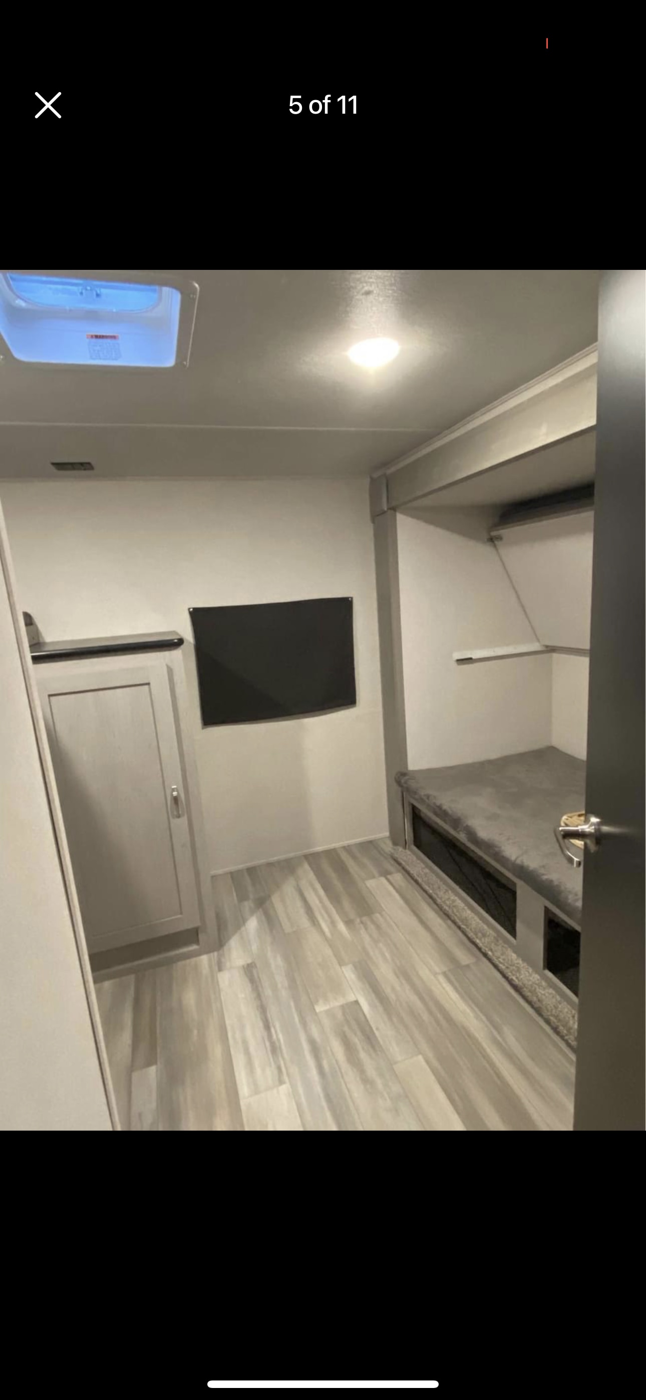 RV rental interior: light wood floors, grey bunk/bed, TV, and storage. Modern and clean design.. Forest River 31bhd 2023