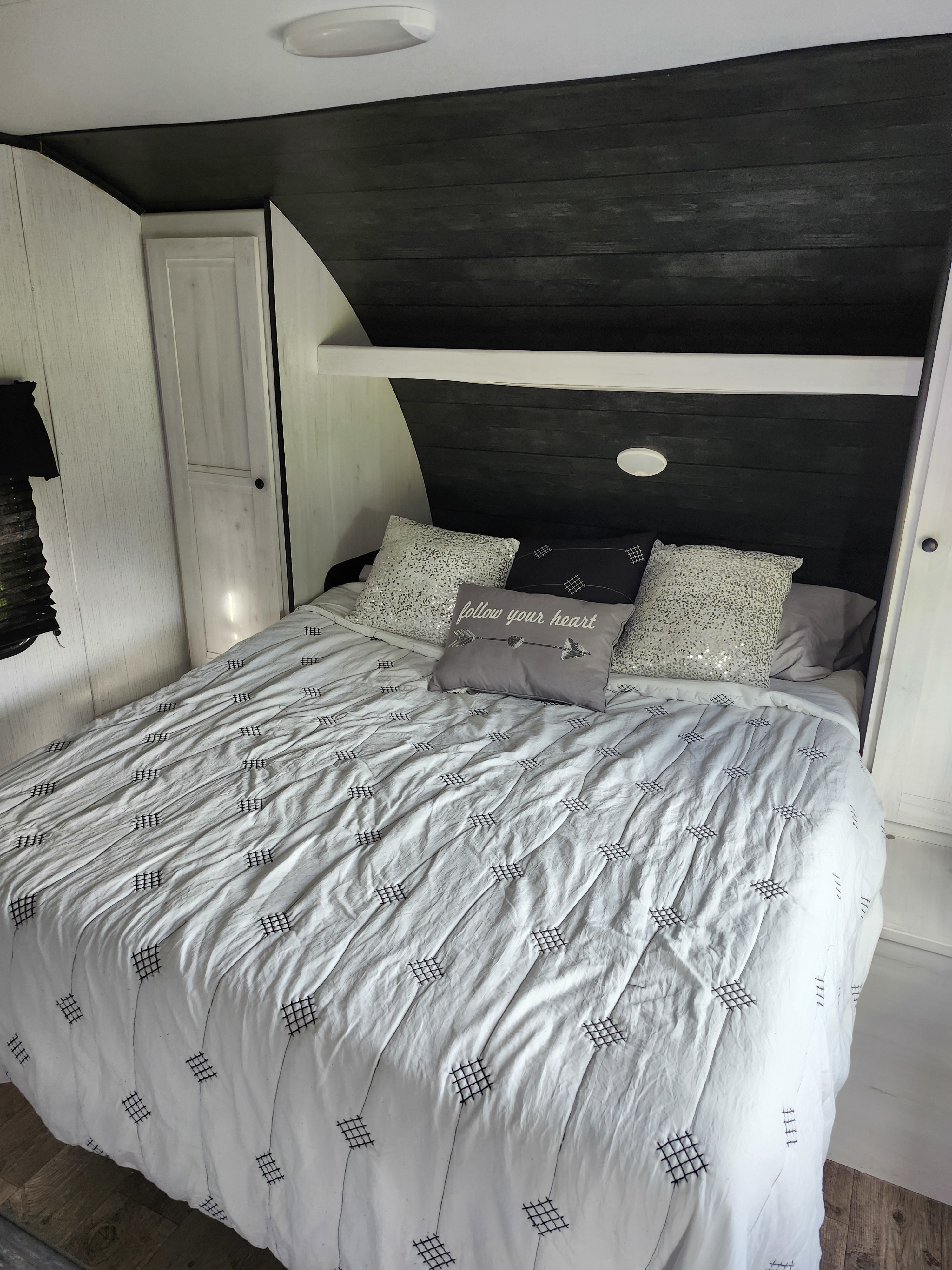 Cozy RV rental bedroom with modern black and white decor, featuring a comfy bed and inspiring pillows.. Heartland RVs Trail Runner 2022