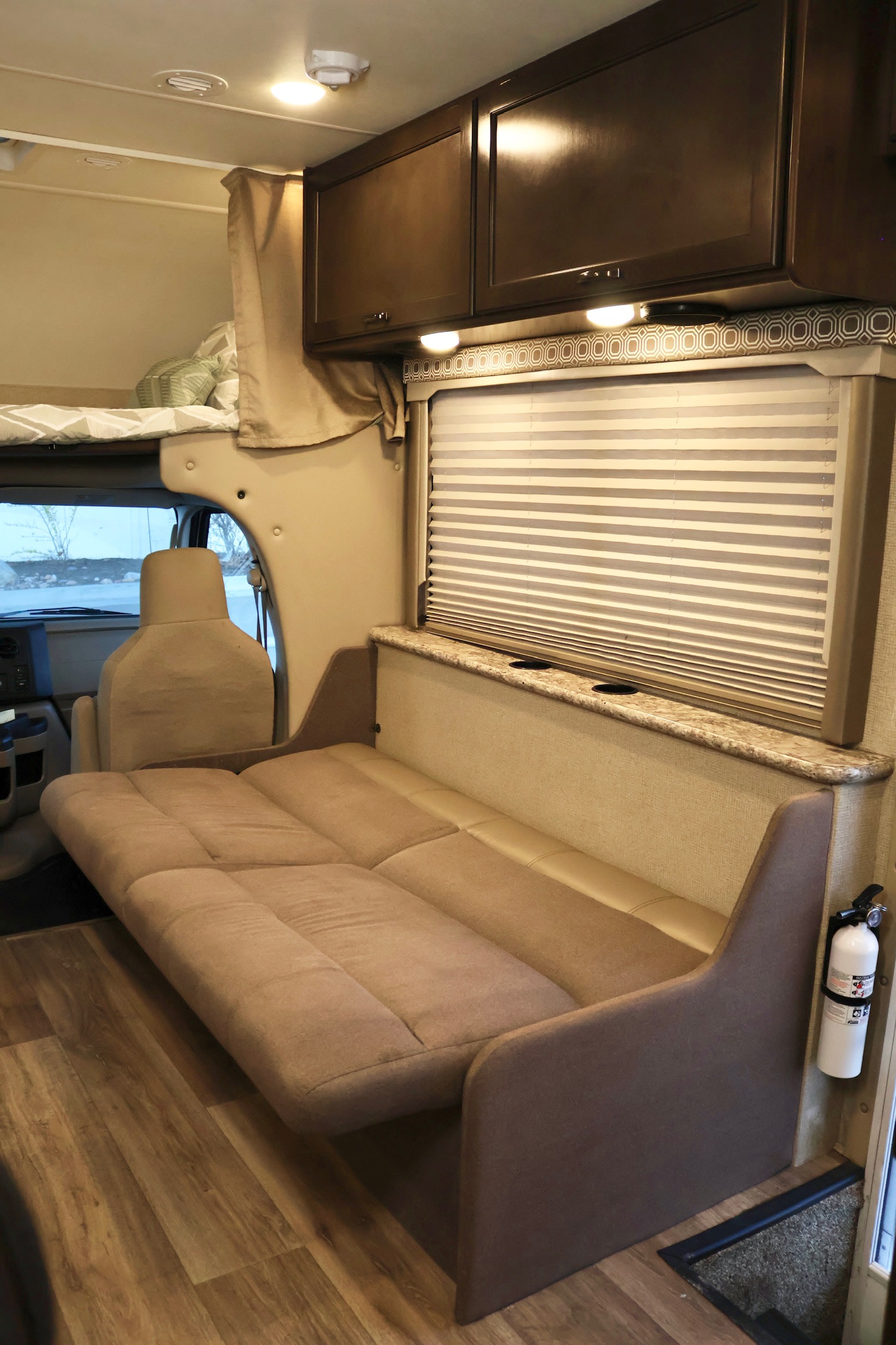Step inside this RV rental's inviting living space with a convertible sofa, overhead bunk, cabinets, and wood-look floor.. Thor Four Winds 2019