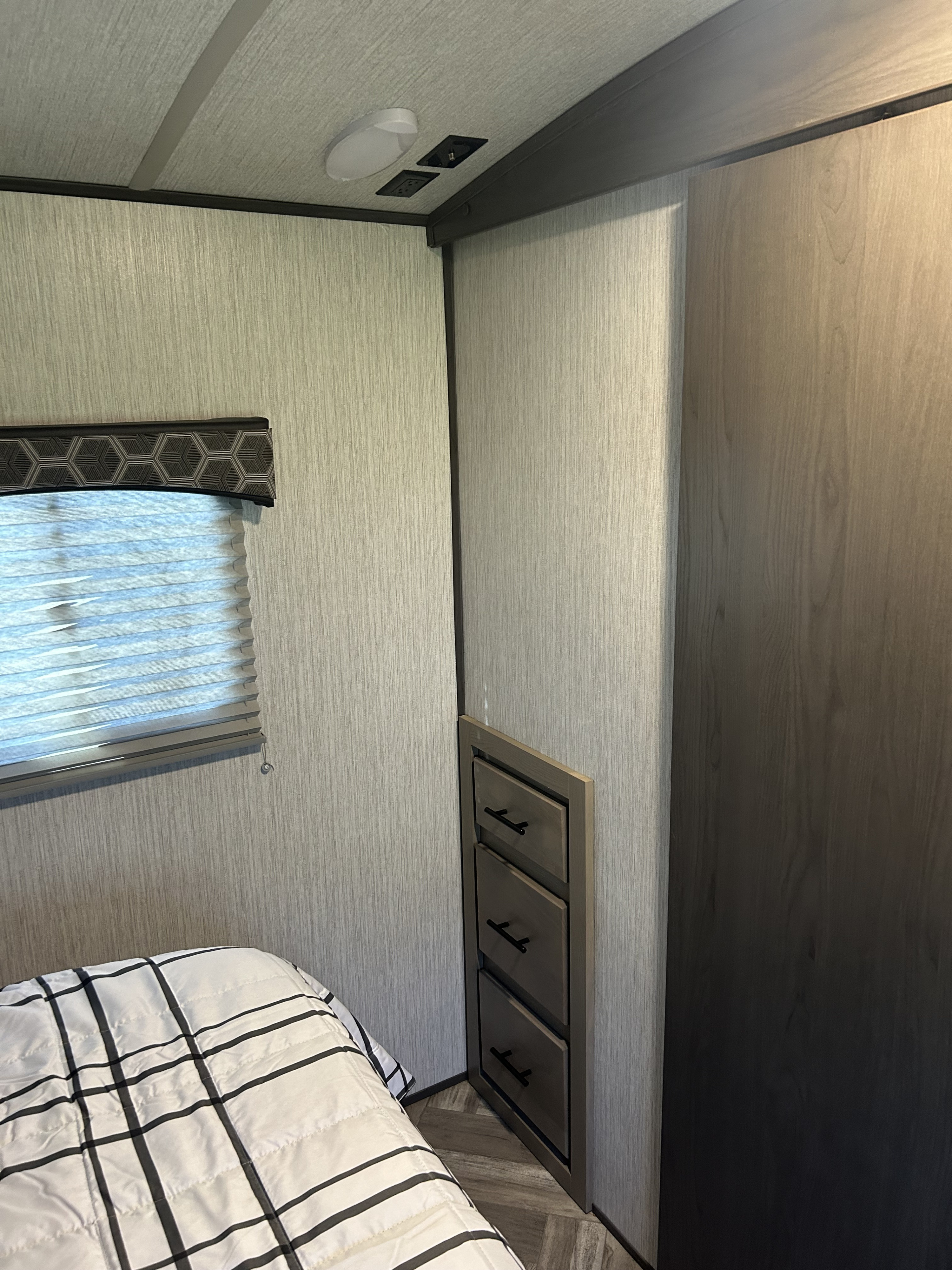 Cozy RV rental bedroom: features a plush bed, window blind, built-in storage, power outlets, and light-textured walls.. Shadow Trailers Shadow Cruiser 2020