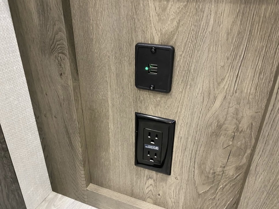Modern RV rental power hub: features a dual USB charger (lit green) and a GFCI protected electrical outlet.. Forest River Surveyor Legend 2022