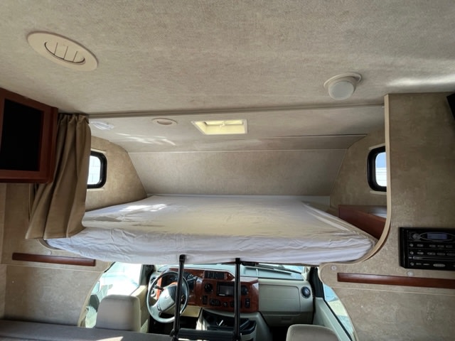 Inside this spacious RV rental, a cab-over bunk bed is visible above the driver's cockpit.. Winnebago Chalet 2014