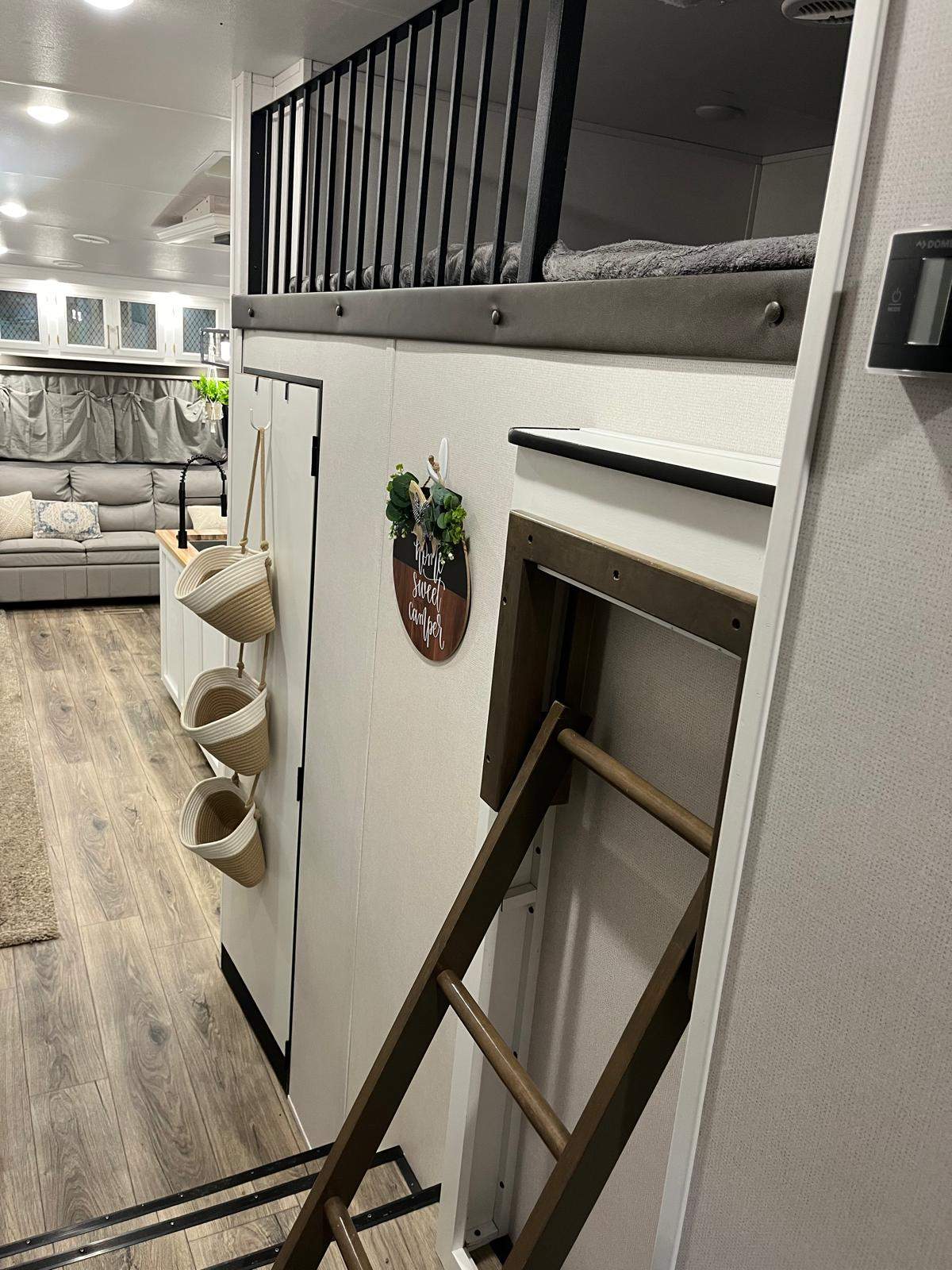 RV rental interior: A built-in bunk bed with black railing, fold-up ladder, main living area with sofa, and kitchen.. Crusader Crusader Fifth Wheel 2021