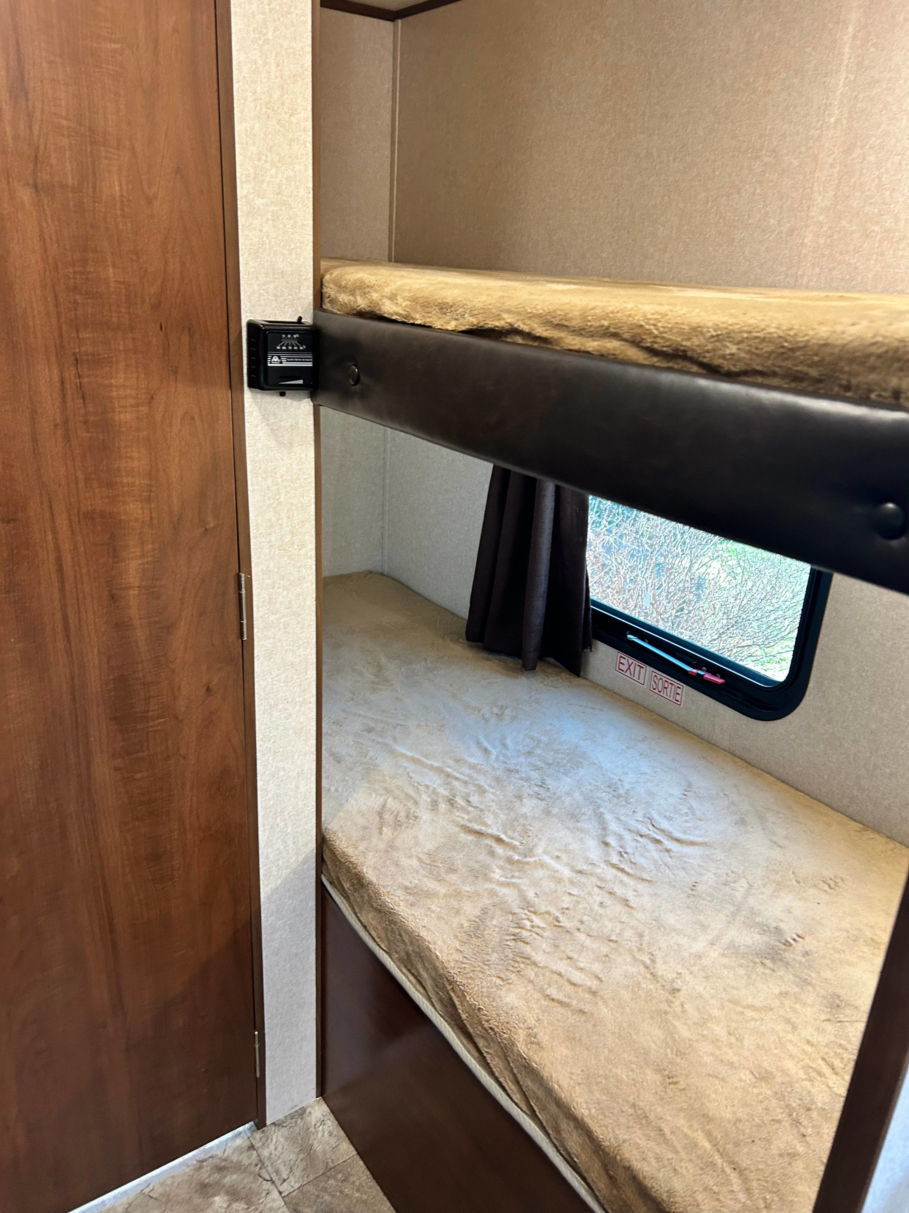 RV rental bunk beds, perfect for family travel. Cozy interior shows two beds, a window with an EXIT sign, and a control panel.. Jayco Jay Flight SLX 2017