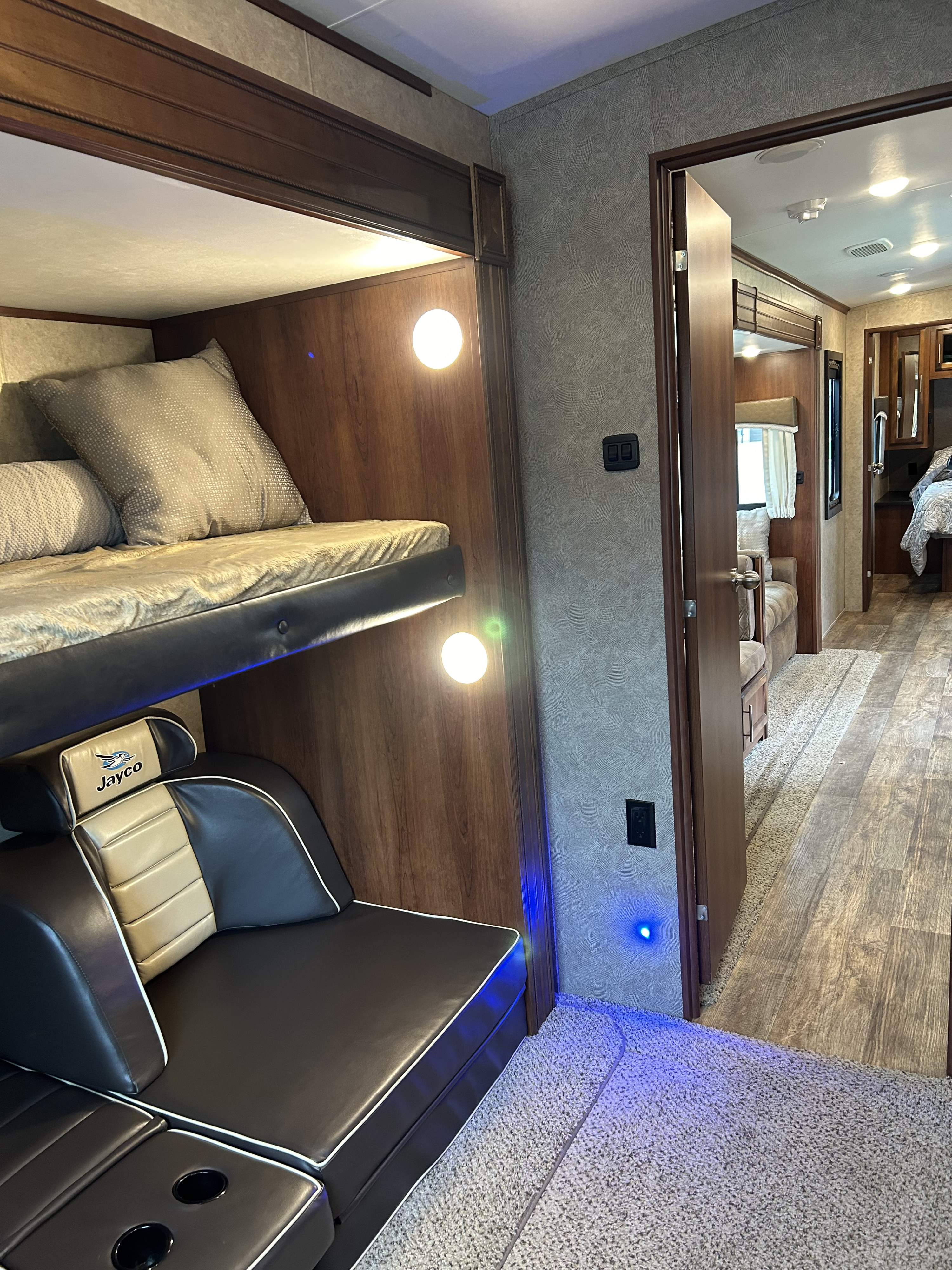 RV rental interior showcasing cozy bunk beds, a comfortable sofa, and bright lighting, leading to other areas of the camper.. Jayco Eagle HT 2018