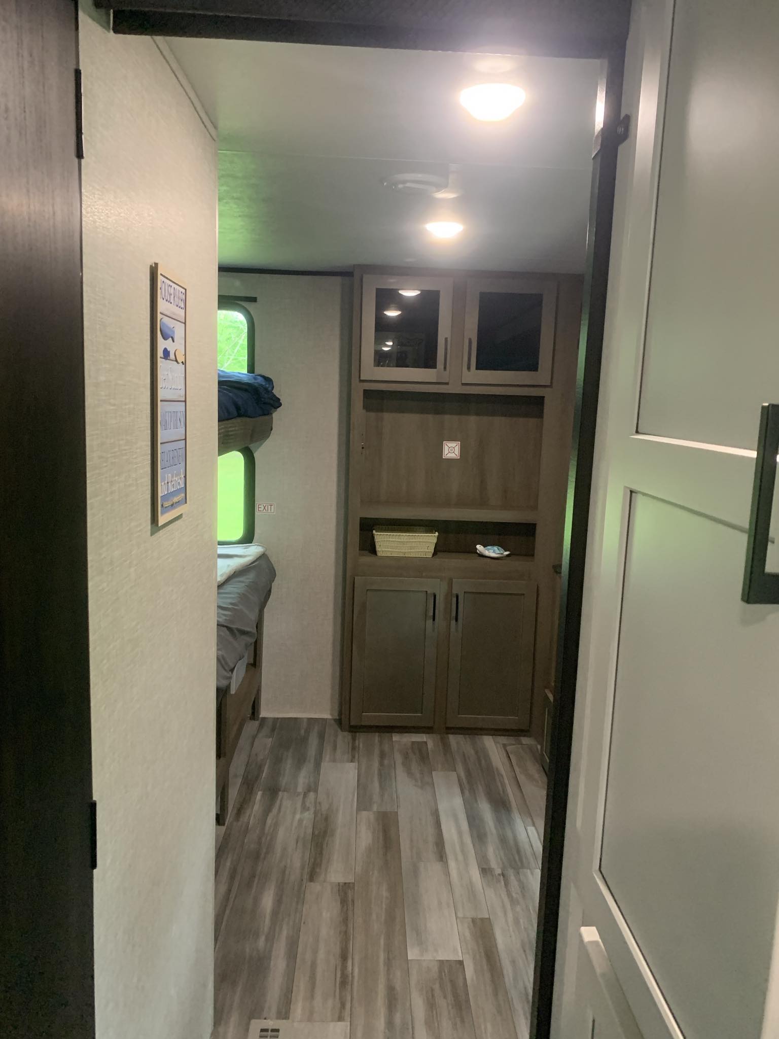 Inside this modern RV rental: a hallway leads to bunk beds with a window view and built-in storage cabinets. Ideal for travel.. Jayco Jay Flight 324BDS 2024