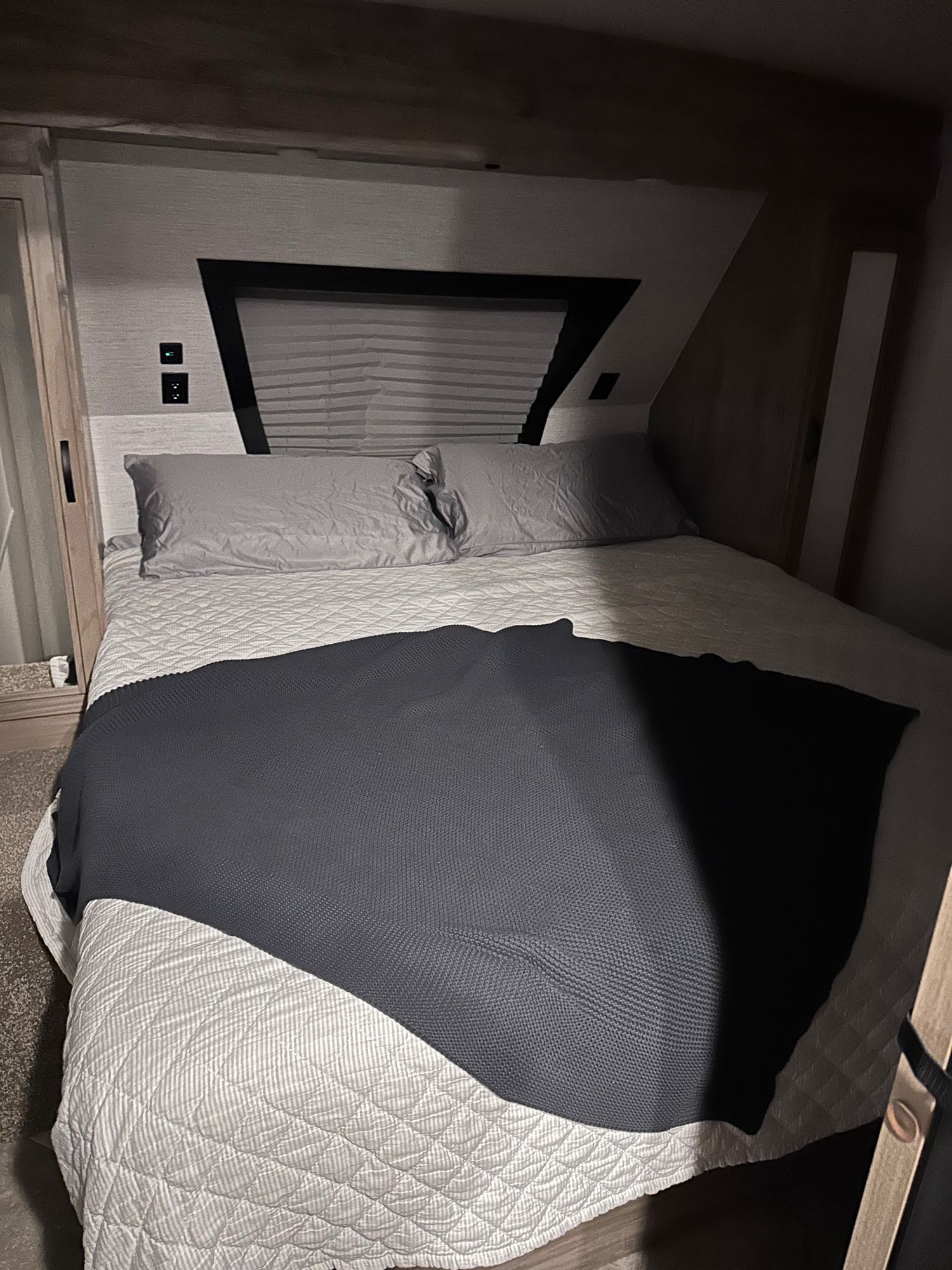 Cozy RV rental bedroom with a neatly made bed, light quilted comforter, gray pillows, and a dark throw blanket.. Forest River Palomino Solaire 2021