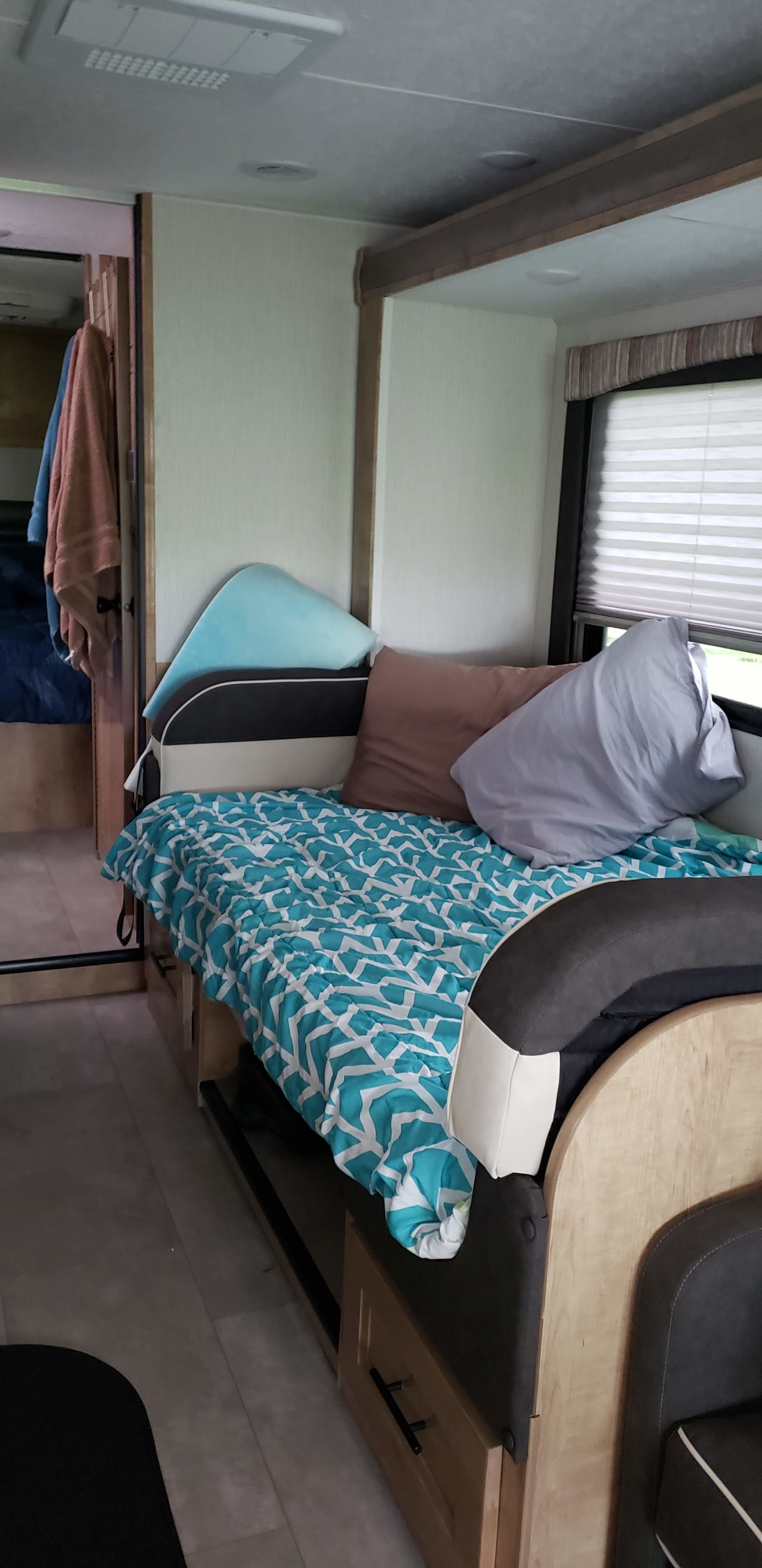 Cozy RV rental interior showcasing a comfortable bed with patterned bedding and pillows, ideal for your next travel adventure.. Forest River Coachmen Leprechaun 2020