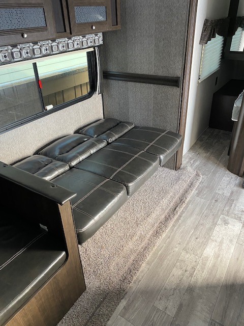 RV rental interior showing a flexible, dark faux leather sofa that converts into a bed for guests or sleeping.. Heartland RVs Pioneer 2019