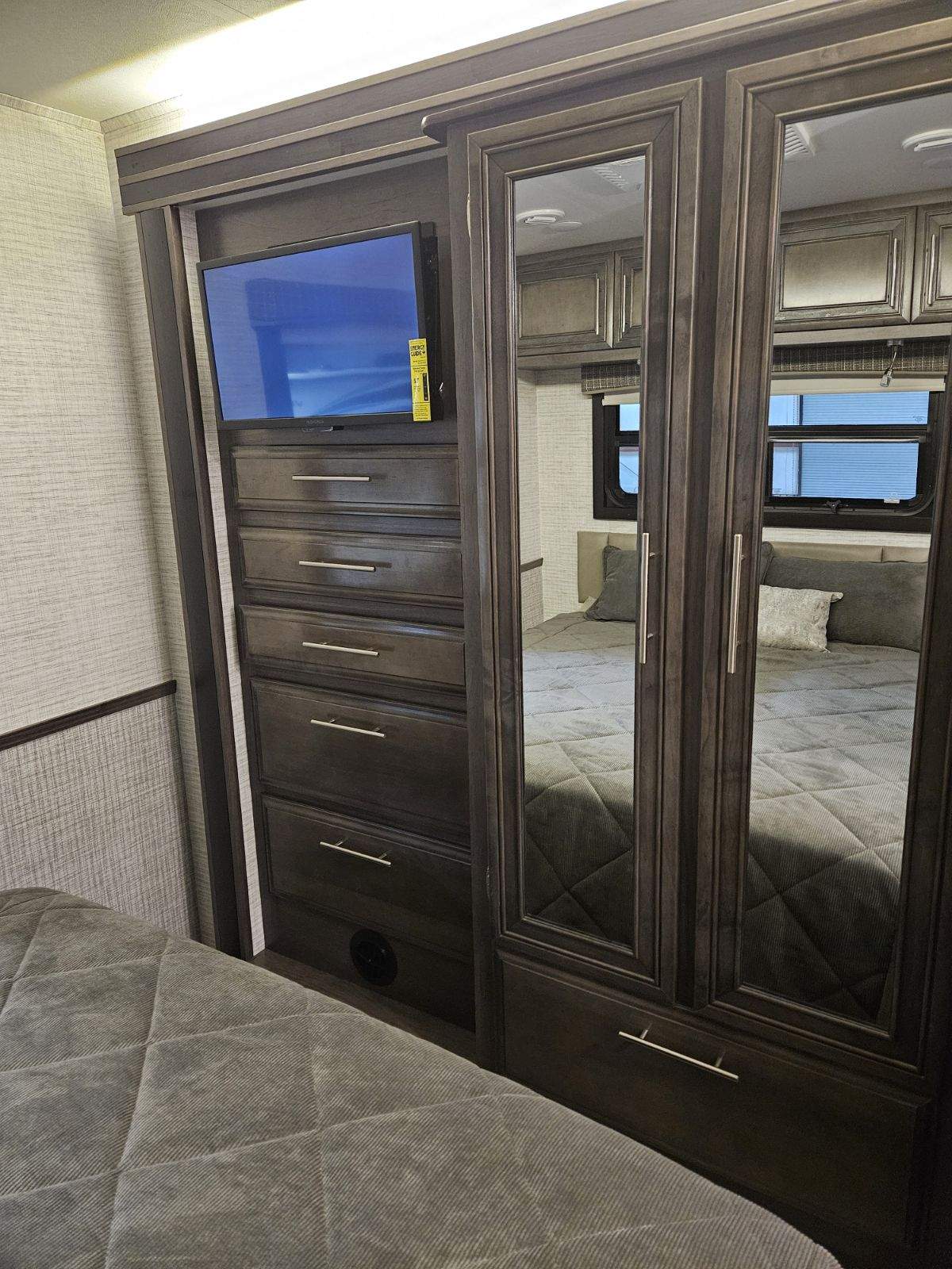 Spacious RV rental bedroom with TV, ample dresser drawers, and mirrored closet for a comfortable stay.. Thor Vision 2024