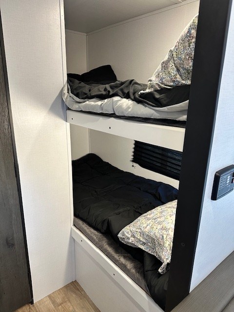 Inside this RV rental: neat bunk beds with dark bedding and patterned pillows, offering cozy sleeping space.. Keystone RV Hideout 2022