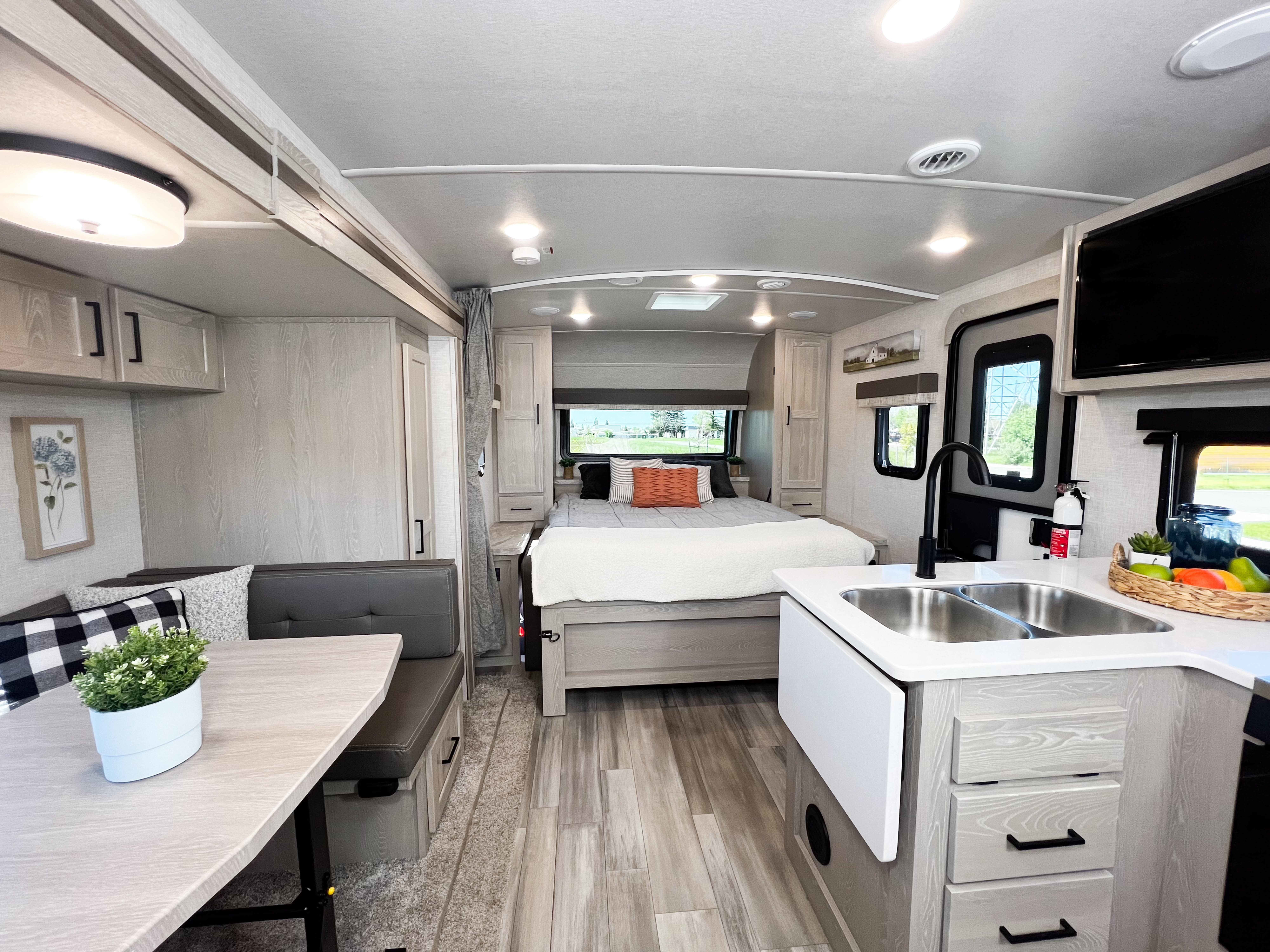 Bright rv rental interior, featuring a compact kitchen, dining area, and cozy bedroom with light wood accents.. Forest River Flagstaff Micro Lite 2022