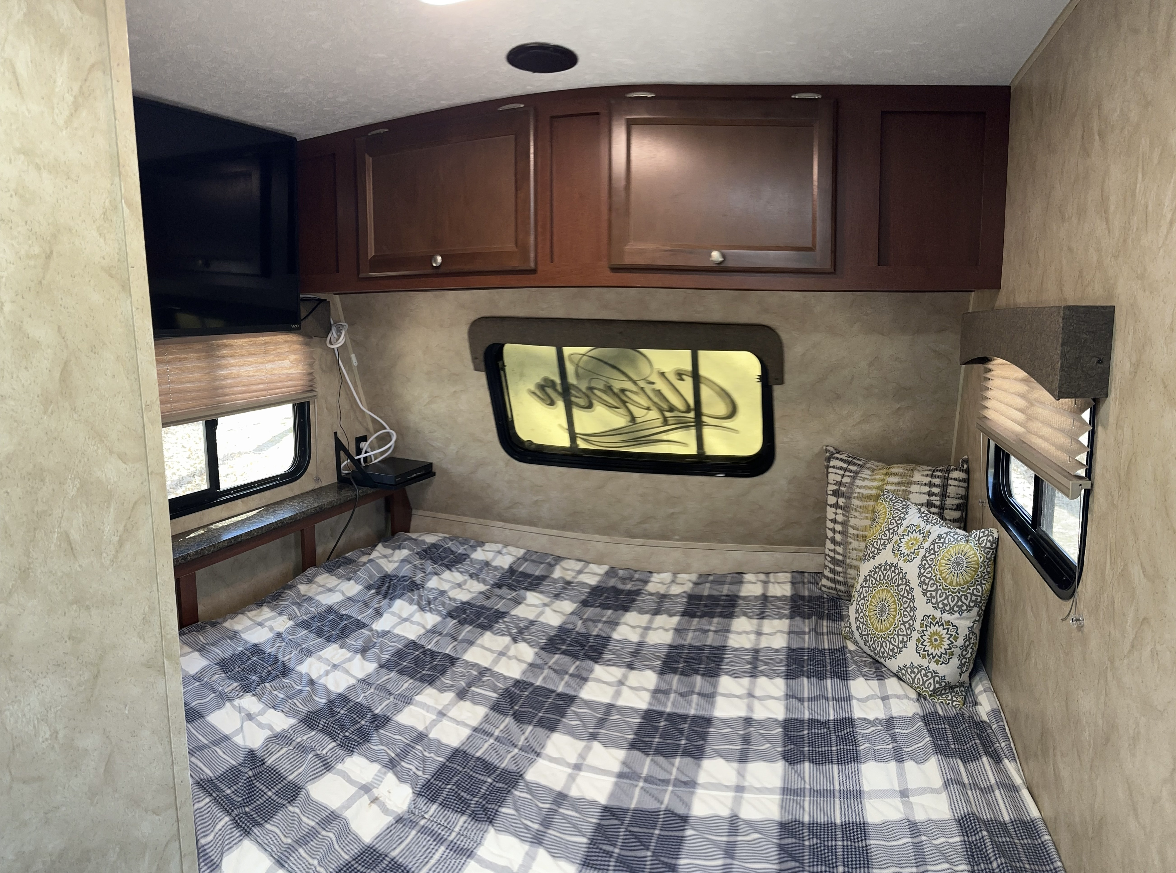 Cozy RV rental bedroom with plaid bed, TV, and overhead cabinets for comfortable stays.. Clipper Clipper Trailer 2016