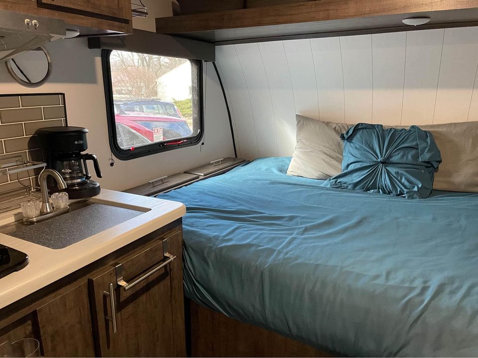 Experience comfortable travel in this RV rental. Compact kitchenette with coffee maker, sink, and cozy bed. RV interior.. Riverside RV Retro 2022