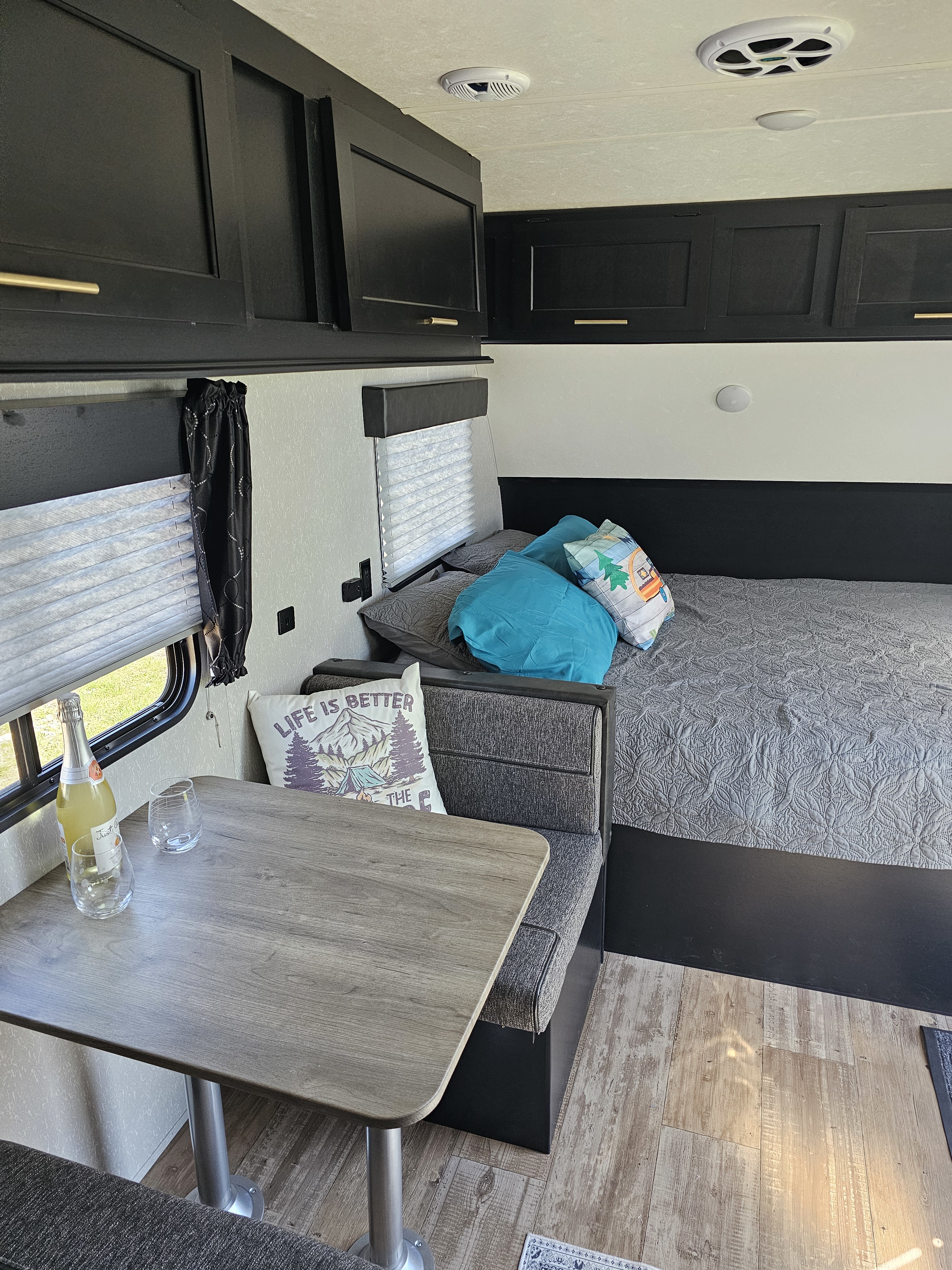 Inside your RV rental: a comfortable sleeping area & dinette with stylish black cabinets & wood floors.. Forest River Cherokee Wolf Pup 2021
