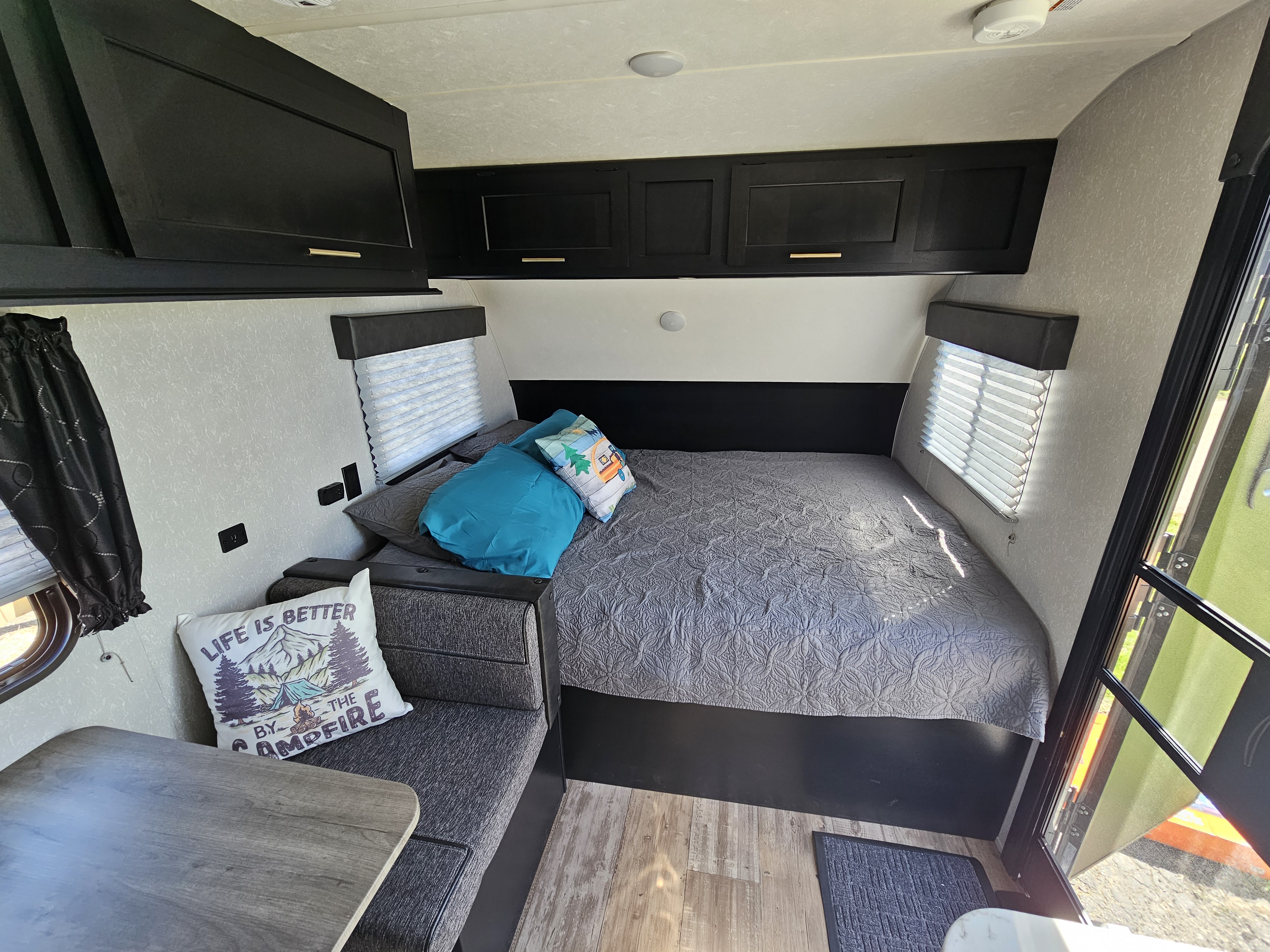 Spacious RV rental interior with a comfy bed, black cabinets, and dinette. Enjoy the journey in this modern camper.. Forest River Cherokee Wolf Pup 2021