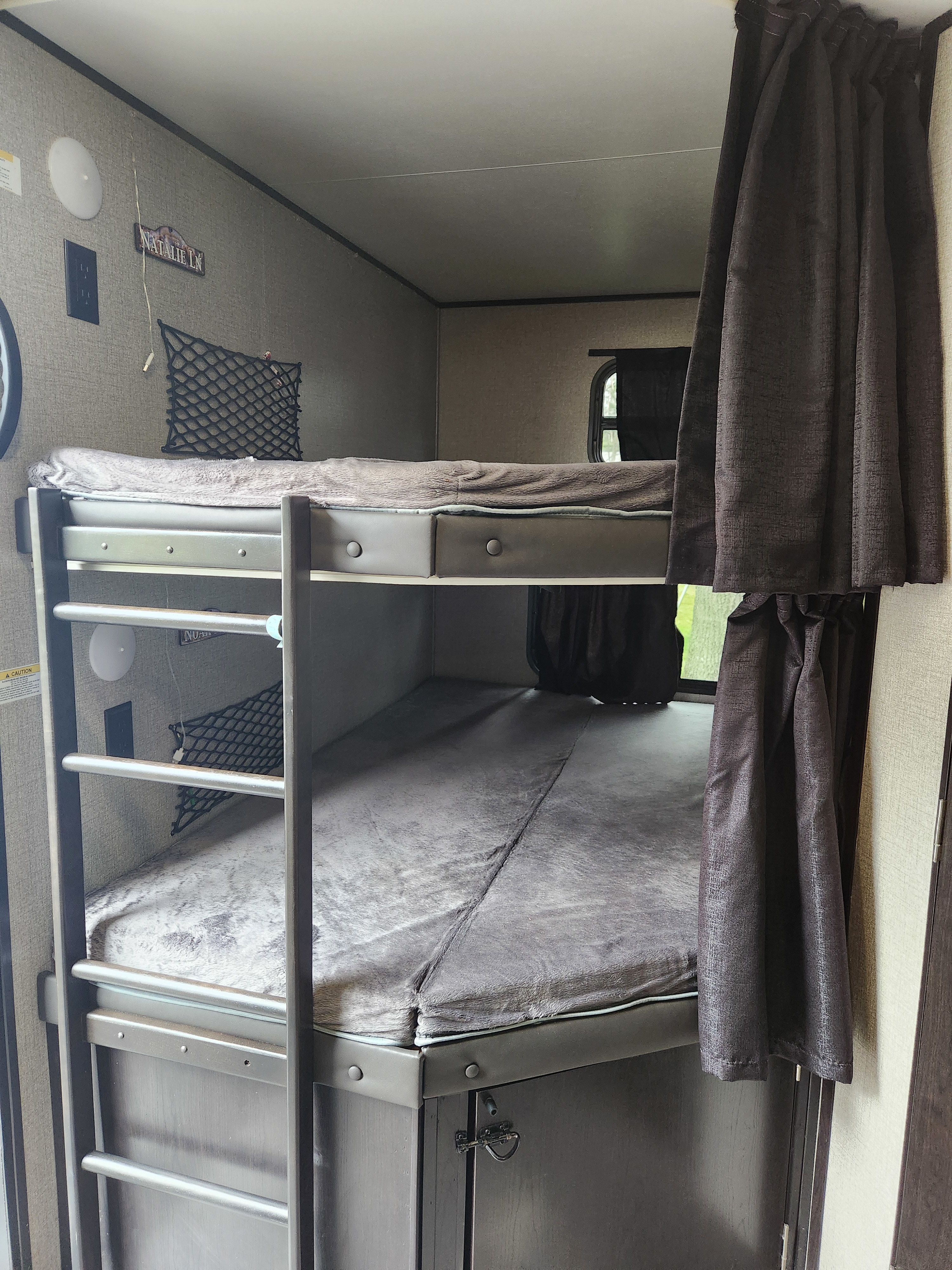 Cozy bunk beds inside an RV rental, featuring a ladder, privacy curtains, and compact storage. Perfect for family adventures.. Jayco Jay Flight 2020