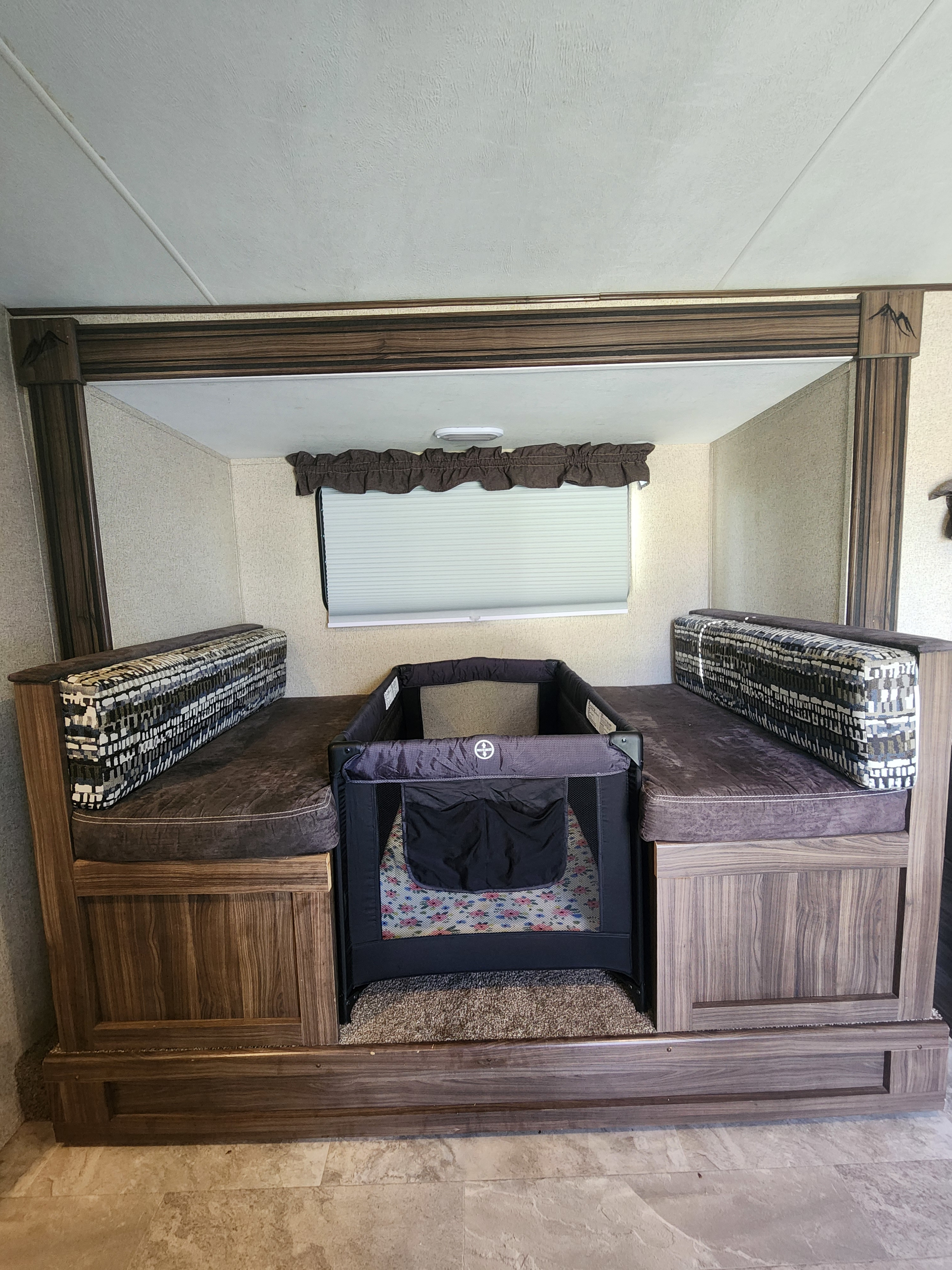 RV rental interior with a baby pack-n-play set up in the dinette booth, perfect for family travel.. Coachmen Apex Nano 2018