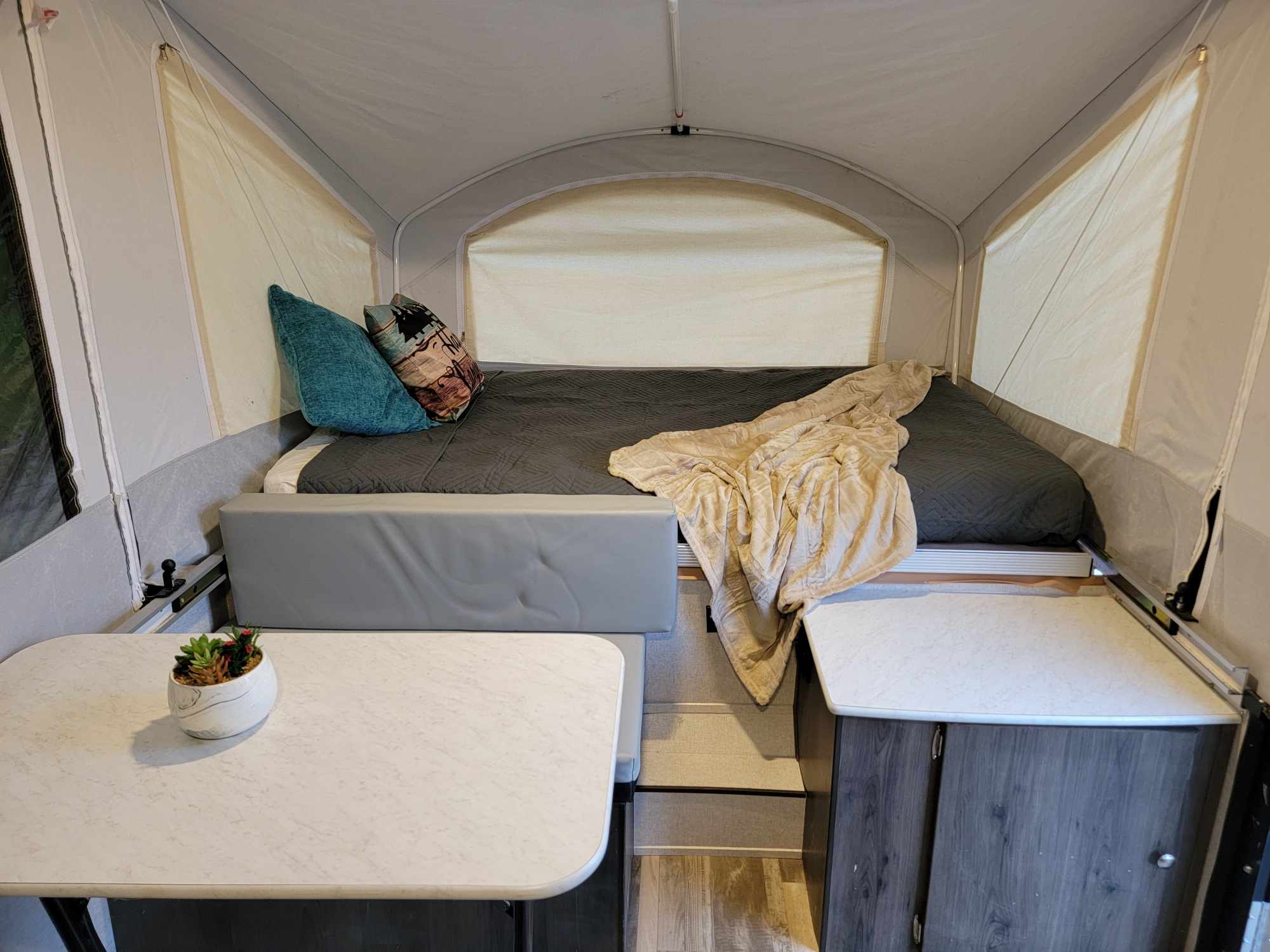 Cozy pop-up RV rental interior with bed, table, and seating. Perfect for comfortable glamping adventures.. Forest River Coachmen LS 2020