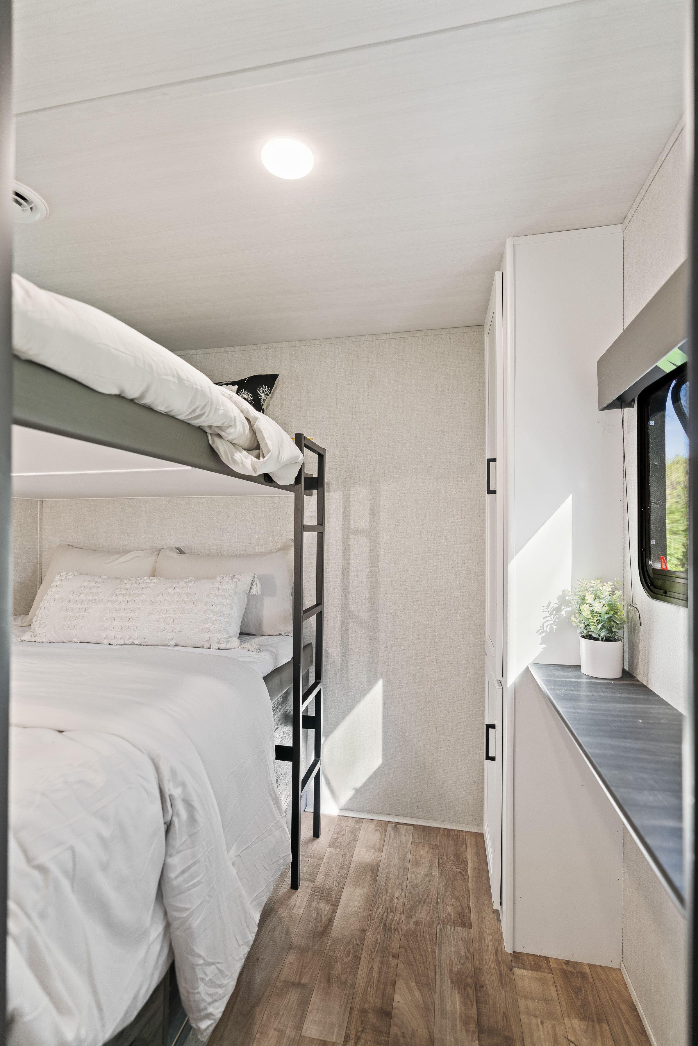 Cozy RV rental interior featuring comfortable bunk beds with white bedding, bright natural light, and ample storage.. Keystone RV Hideout 2022